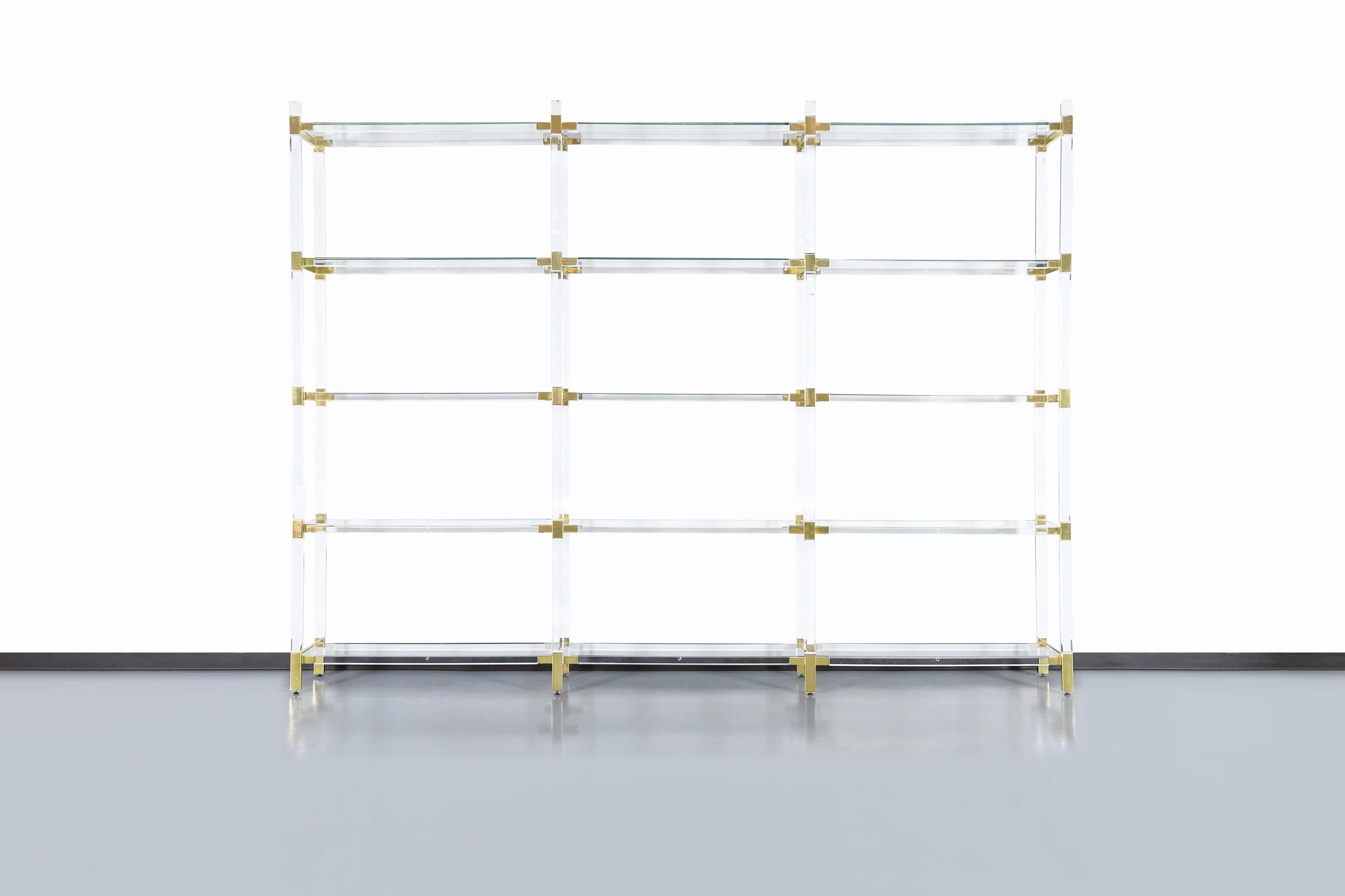 Stunning vintage custom etagere/shelving unit in lucite and brass by Charles Hollis Jones and manufactured in the United States, circa 1980s. Jones was one of the first to use lucite as a unique material, and his innovative approach to furniture