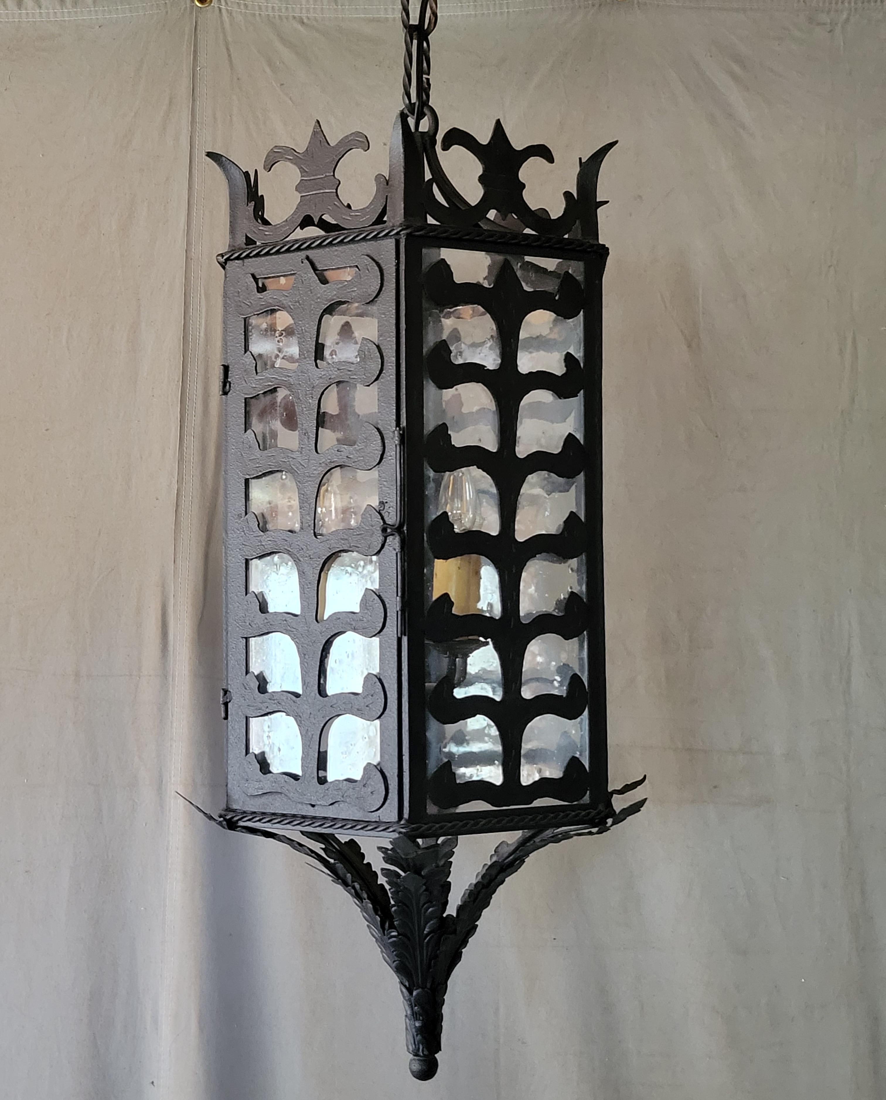 A gorgeous vintage custom hexagonal black iron & glass pendant lantern with 3 flame light bulbs.  Each of the six sides is made up of glass panels and decorative ironwork designs. Glass contains bubbles and irregularities to give it an antique look.