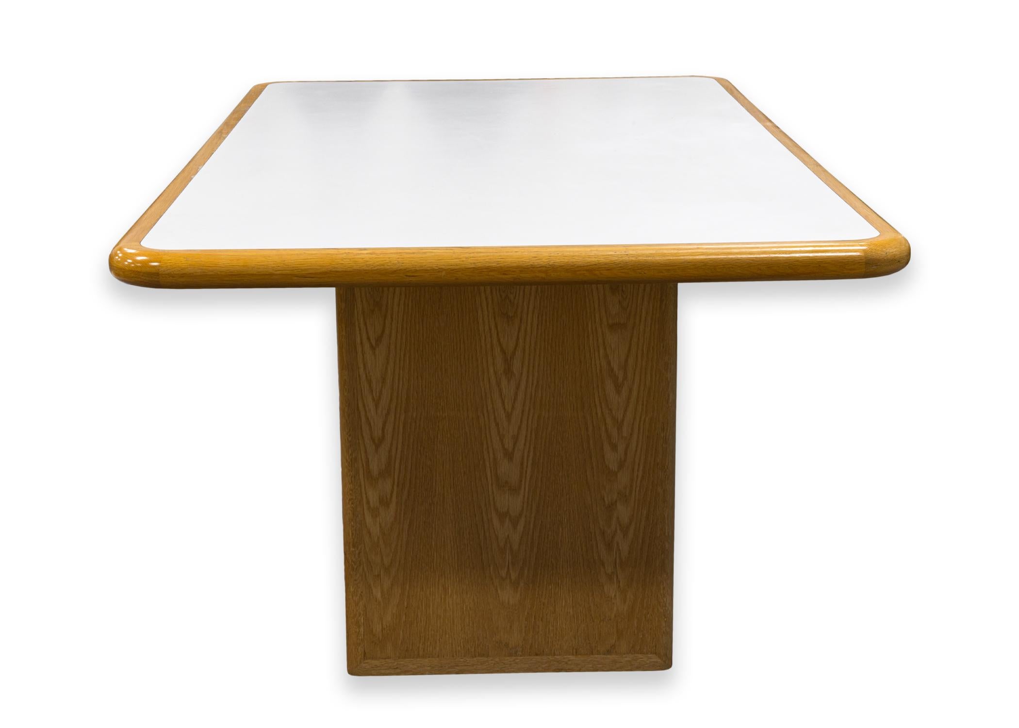 A vintage custom made Tobocman dining table. This is a gorgeous custom made table featuring a rounded rectangular shape, two thick pedestal legs, and a white laminate table top with a light wood frame. This table is in very good condition with some