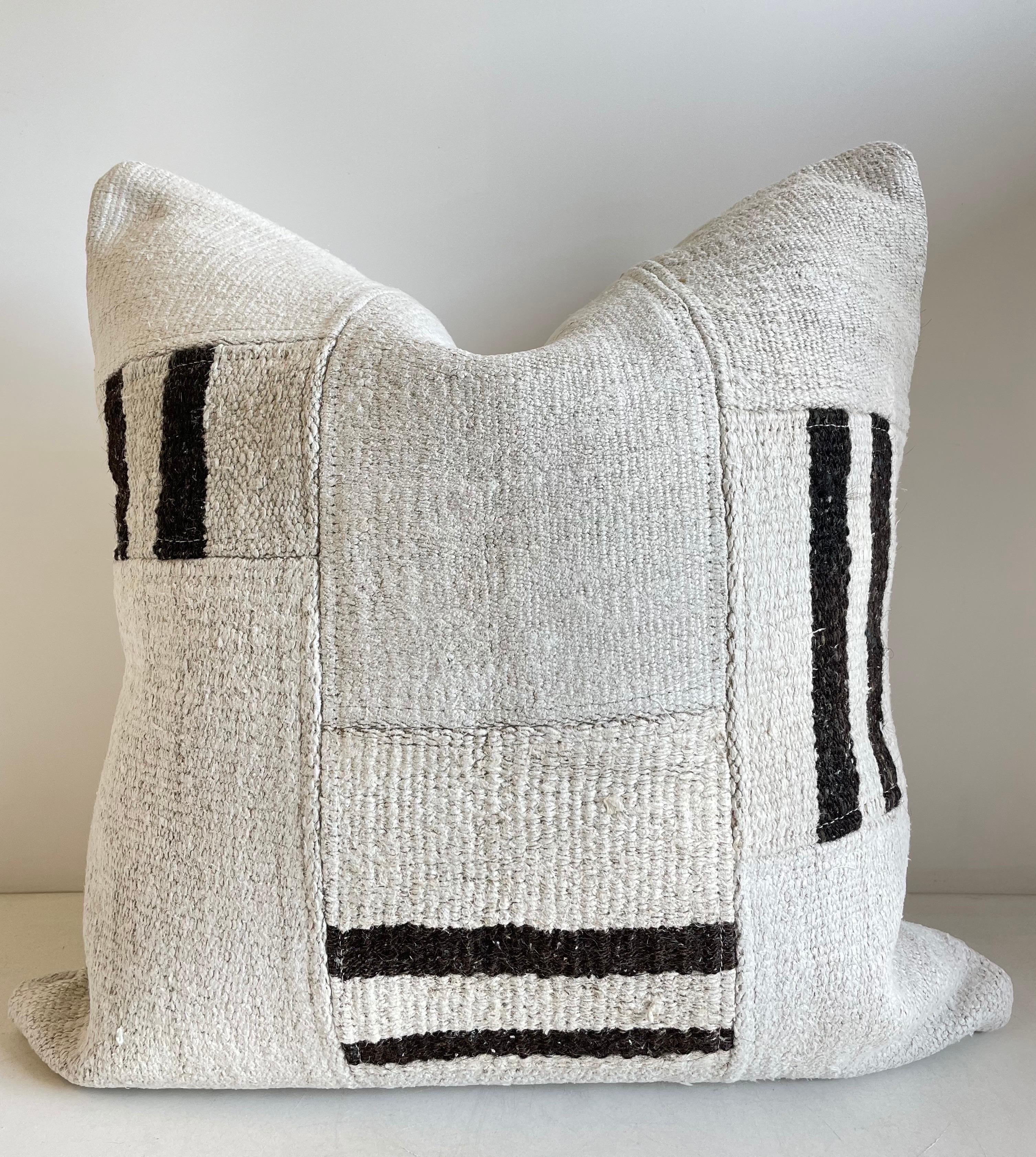 Creamy white hemp rug patchwork style pillow. Unique patchwork pillow has been made with parts of different Turkish rugs, in multiple white tones and stripes in brown. Double sided rug pillow has patchwork on both sides, and hidden zipper closure.