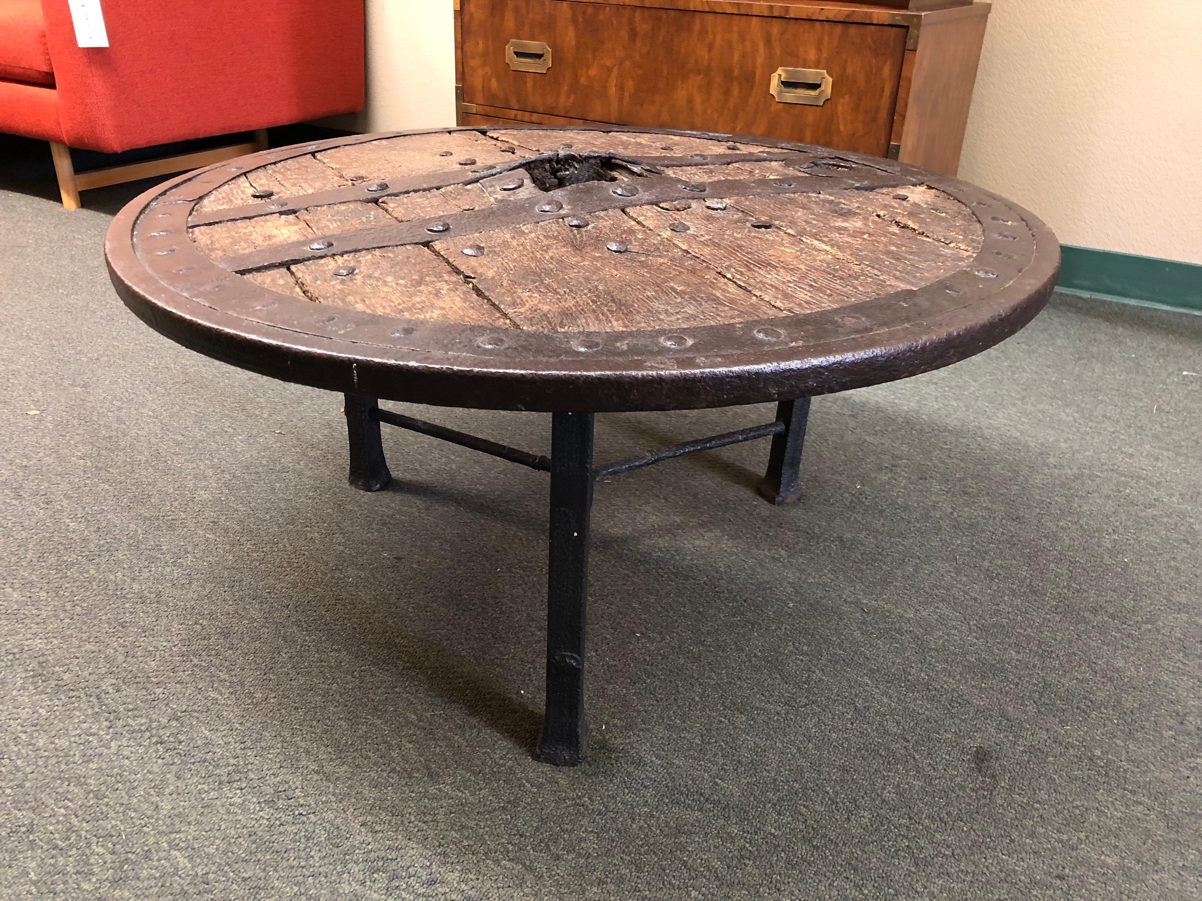 This is a unique antique European wagon wheel that's been repurposed as a table. The piece has been complemented by a hammered iron base. A heavy piece, it is a wonderful statement piece for home or office.
 