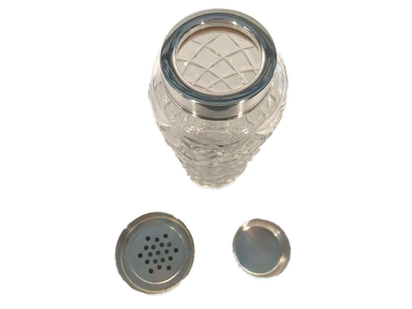 Vintage cocktail shaker of clear glass cut in a diamond pattern with a silver plate collar and center-pour strainer lid.