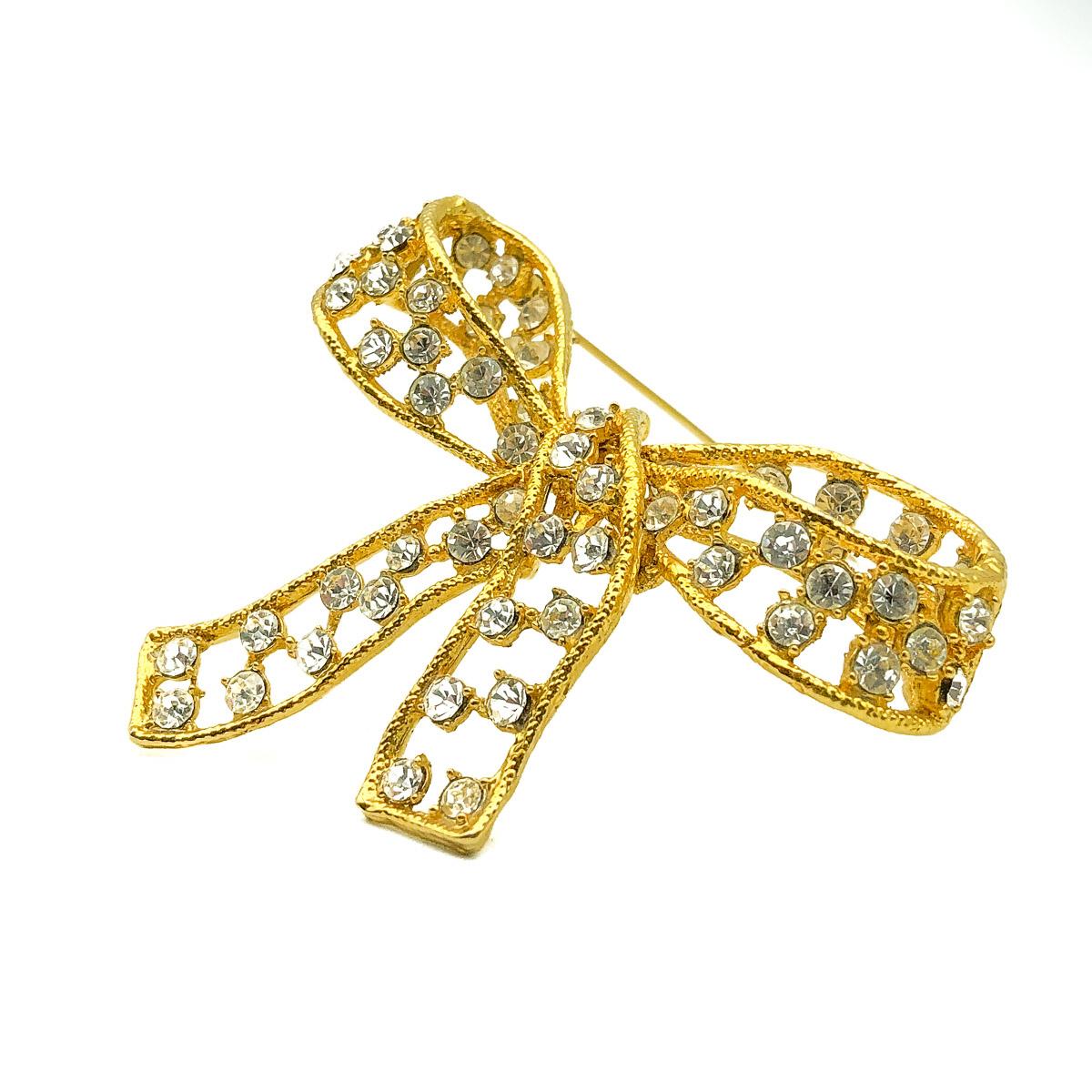 Vintage Crystal Bow Brooch. Crafted in gold plated metal and crystals. Featuring a large three dimensional, floppy bow design with a myriad of crystals. In very good vintage condition and approx. 7cm.  A perfectly timeless pin with an ultra feminine