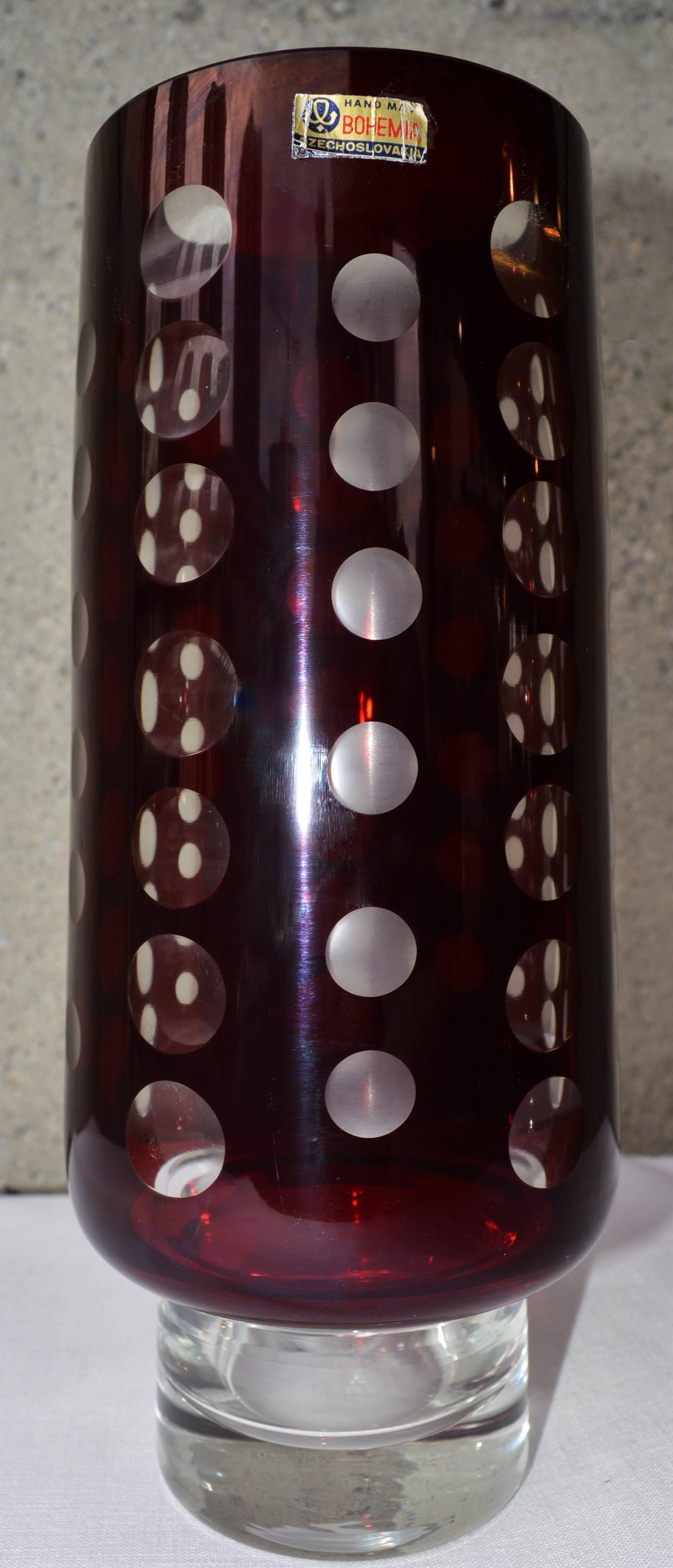 This stunning handmade vintage Czech Bohemia glass vase is a rich burgundy glass cased in white. The artisans cut-away discs out of the red, to create apertures to view through which create beautiful optical illusions. In this vase, clear circles