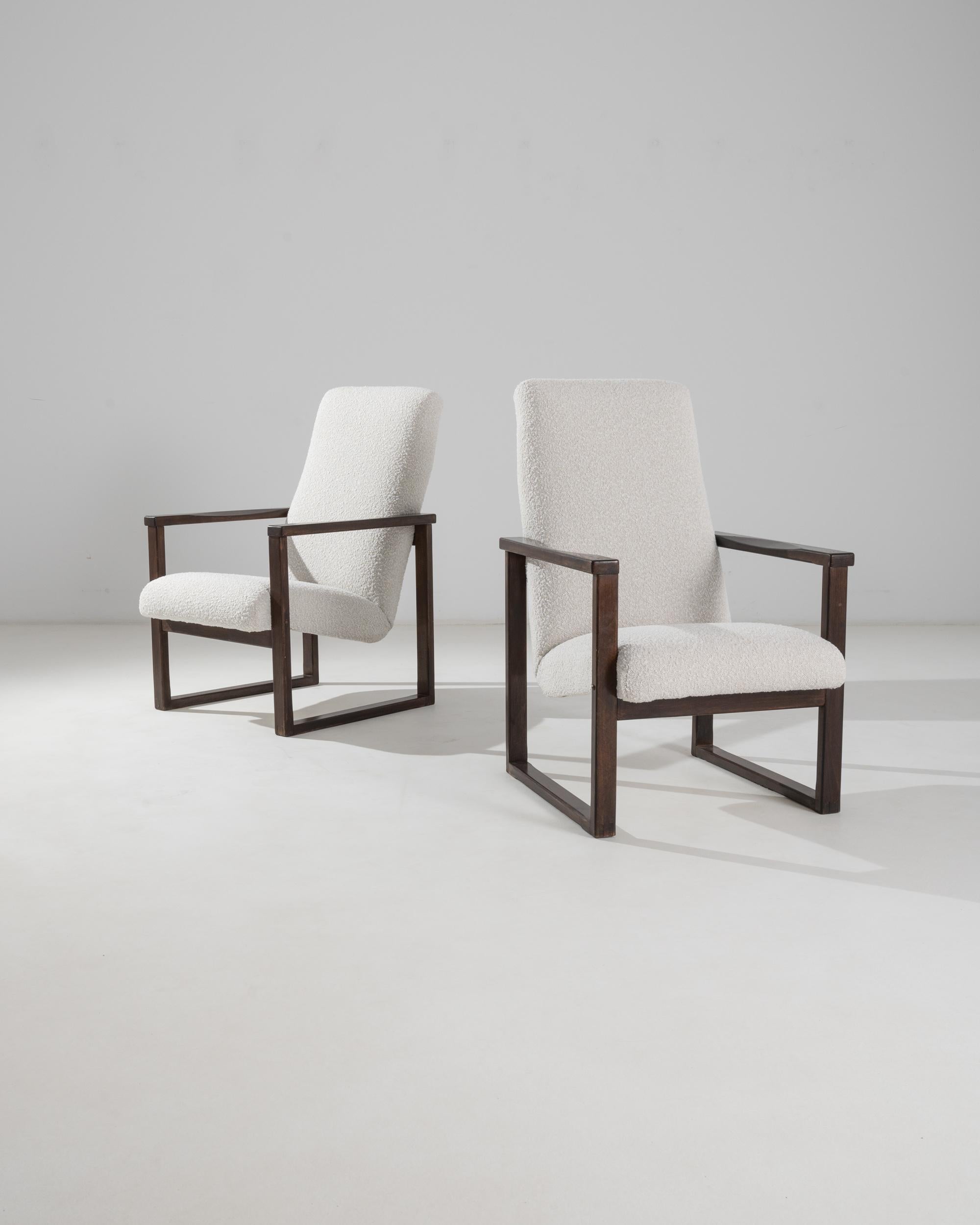 The graphic silhouette of this pair of vintage Modernist armchairs makes a striking impression. Made in Czechia in the 20th century, a cushioned seat appears to float weightlessly between two perfectly square frames of polished wood. This ingenious