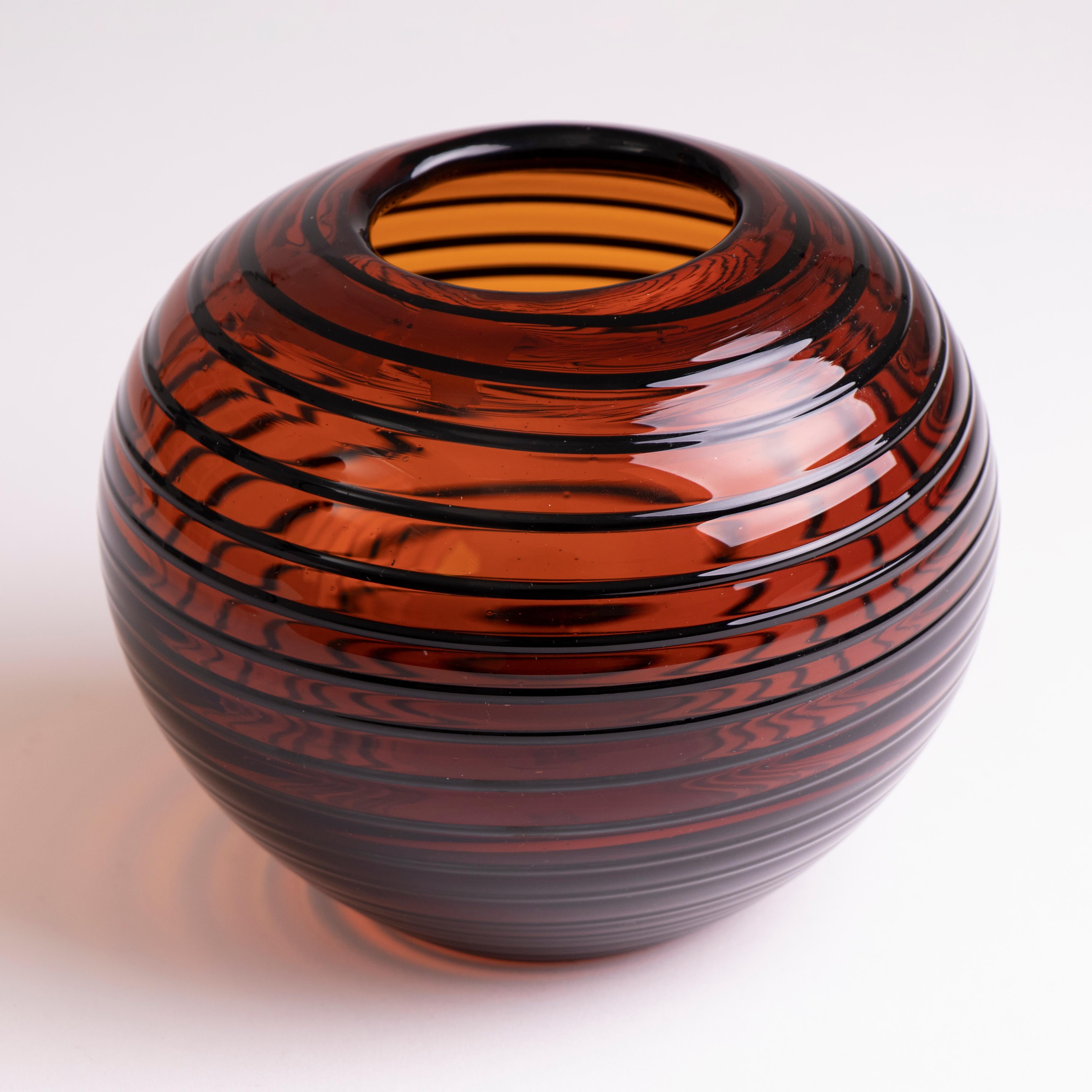 Vintage Czech Tarnowiec amber glass round vase with a deep black swirled pattern around the exterior. A perfect gift. The original label is on the base.

Dimensions: Depth 150mm, width 150mm, height 130mm.