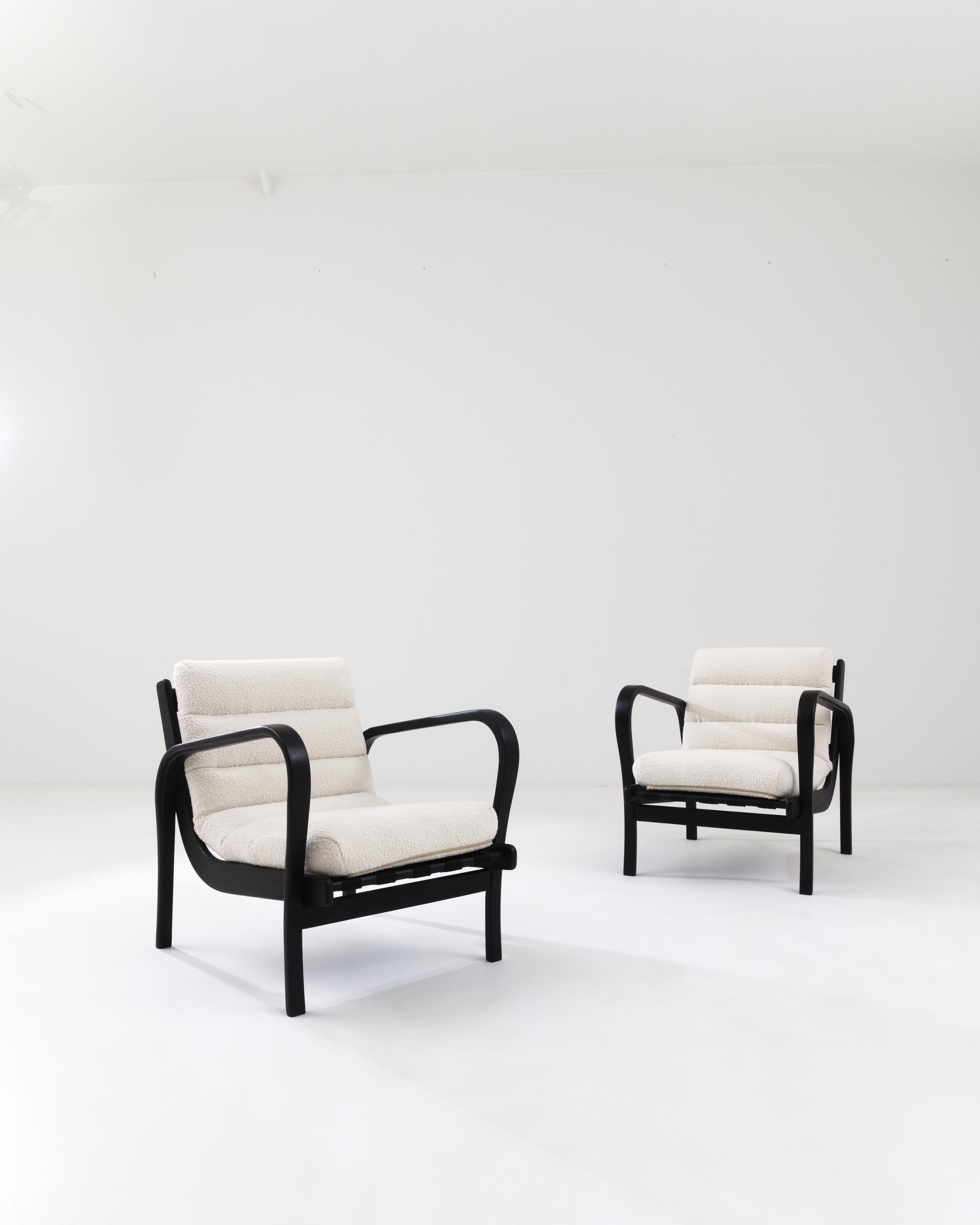 A pair of wooden upholstered armchairs from mid-20th century Czechia by Karel Kozelka and Antonin Kropacek. Characteristic of mid-century Czech design, this pair of armchairs combines a straightforward industrial construction with a sleek and