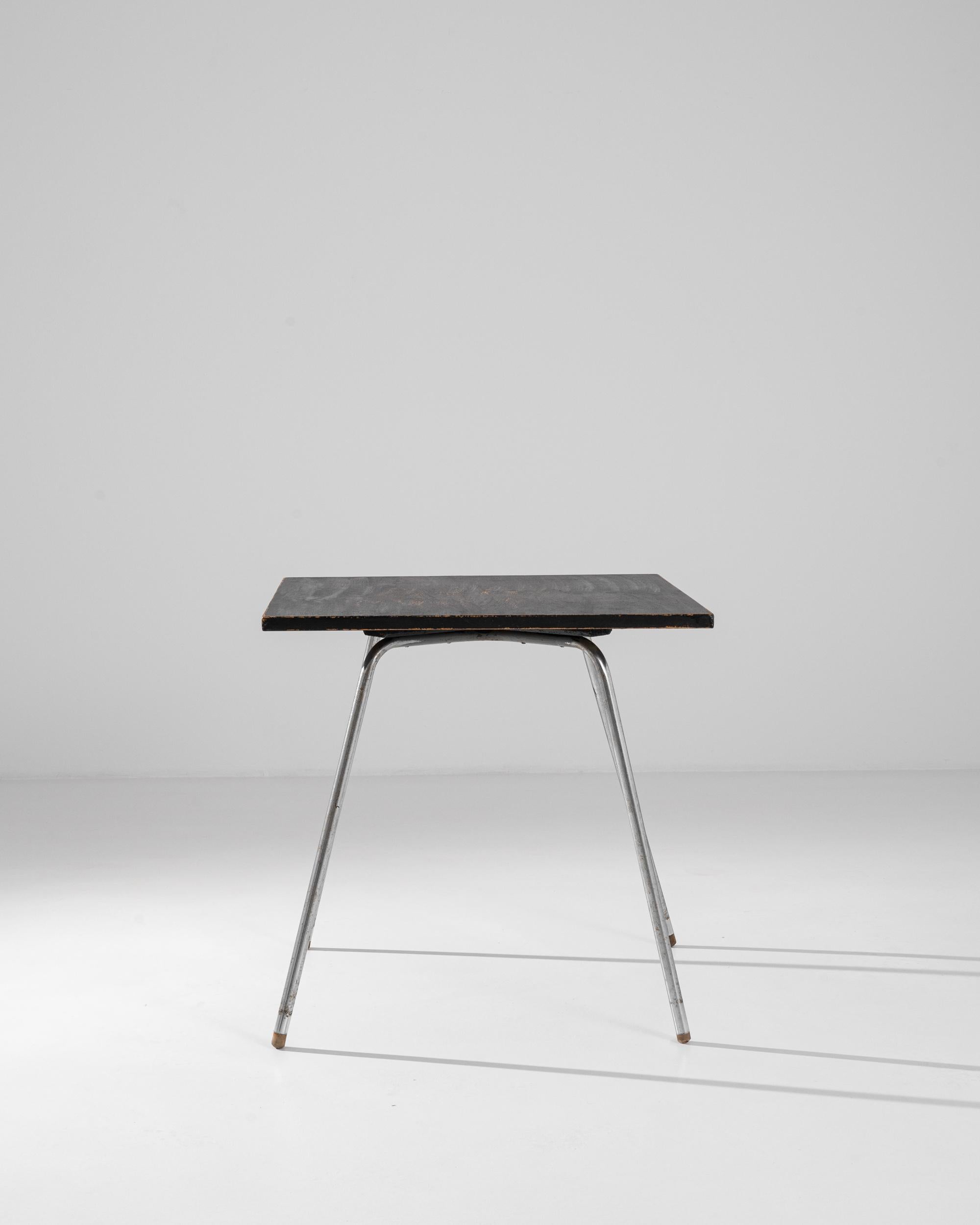 A 20th century Czech tubular steel table with a painted wooden top. This small table is composed of a minimal steel structure which criss-crosses underneath a square top. A light patina has spread across its top and legs, providing a lively texture.