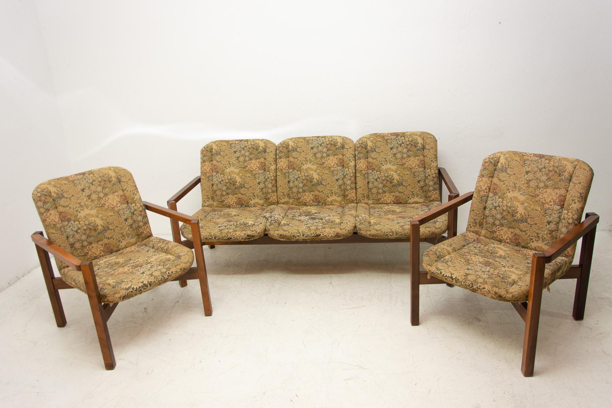 This lounge seating group was made in the 1980s in the former Czechoslovakia. Consists of one sofa and two armchairs. The set is upholstered in fabric. The structure is probably made of pine wood. The furniture is in good vintage condition, shows