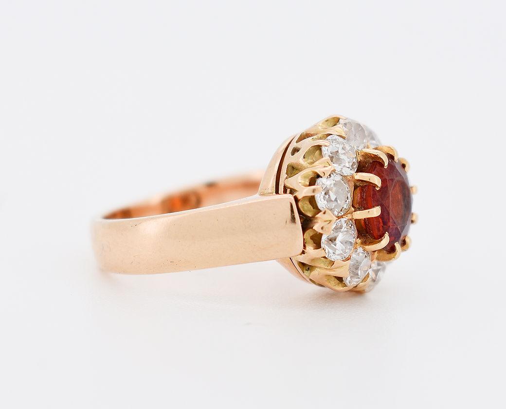 Vintage Daisy Ring (circa 1900) in 14-Carat Gold (585 thousandths). It features a central Spessartite Garnet weighing approximately 1.50 carats, surrounded by 10 old-cut diamonds totaling approximately 1 carat.

Detailed Characteristics:

Weight: