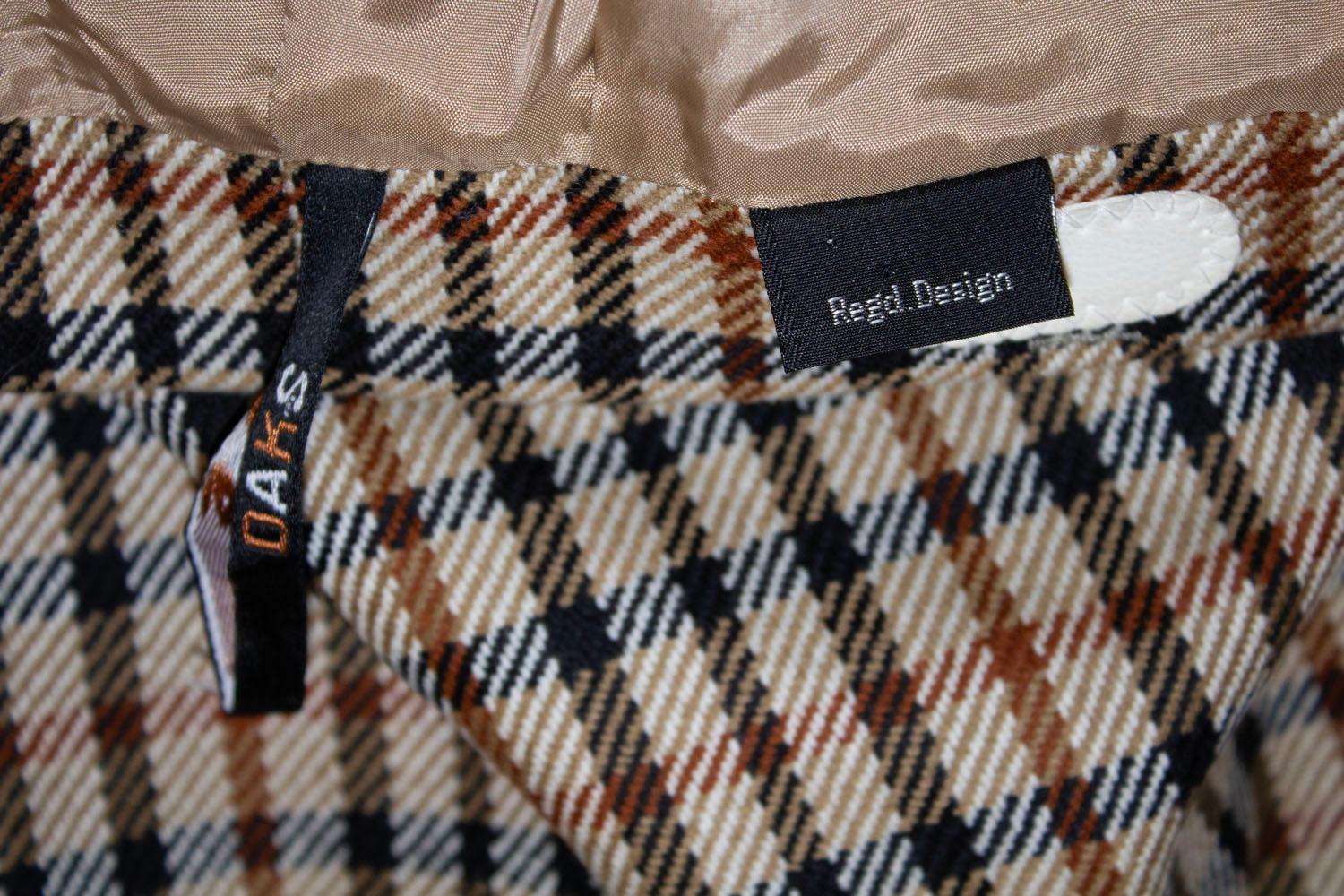 A chic and easy to wear vintage wool skirt by Daks. In a cream , black, brown and rust colour check, the skirt has one pleat at the front and rear, a pocket on either side at the front, back central zip and belt hoops. Made in 1976
Excellent
