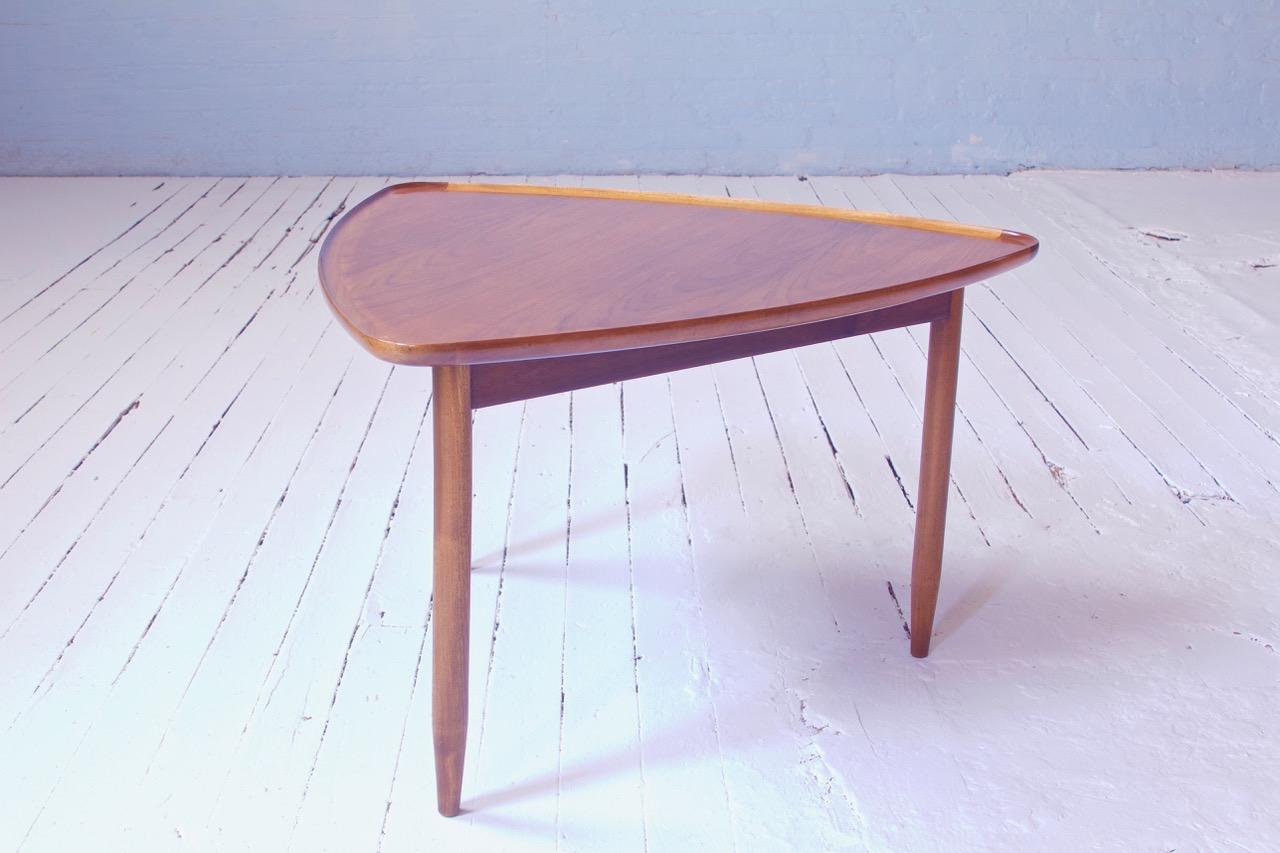 An attractive and useful side table by Arne Hovmand-Olsen featuring a three-legged base and unique reuleaux-triangle-shaped top, comprised entirely of sculpted and turned figured teakwood. The variegated tones of the timber add a beauty and