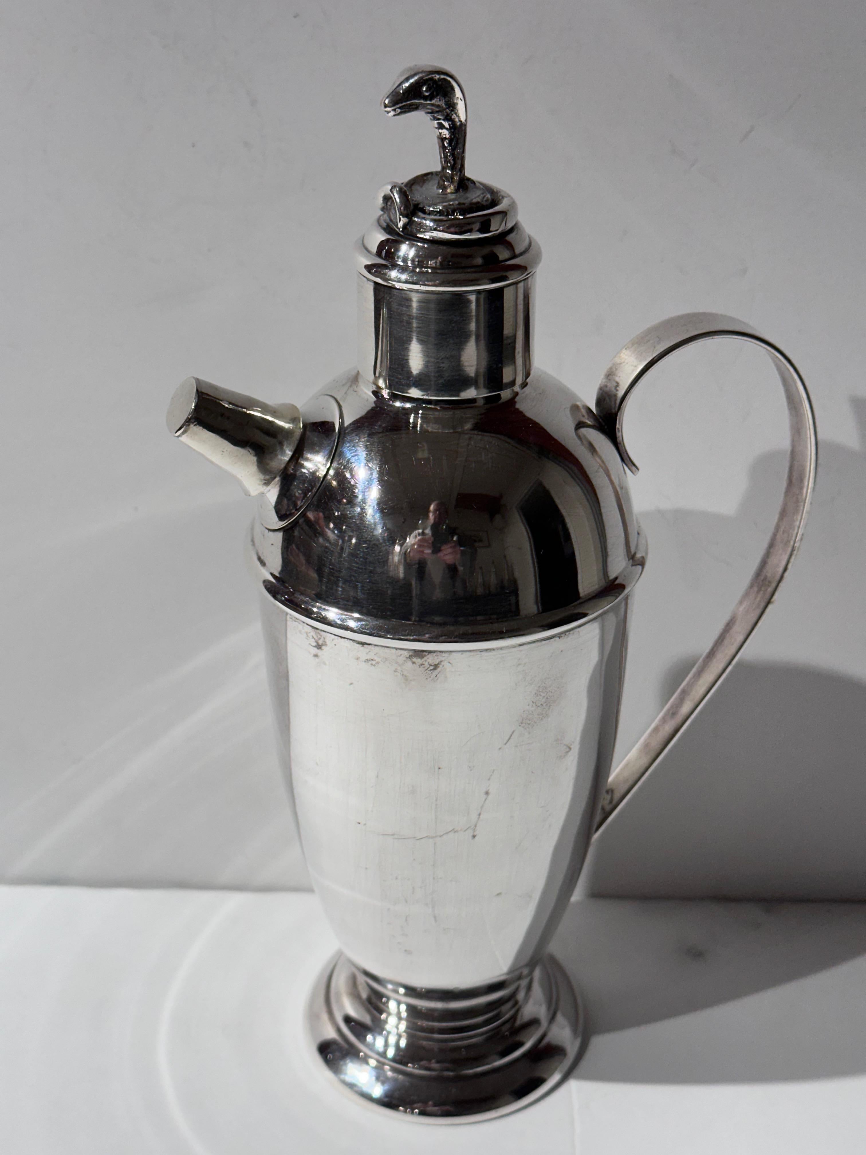 This Vintage Danish Art Deco Silver Plated Cocktail Shaker by Prima Sølvplet is a rare and stunning piece of functional art. The shaker features an unusual top adorned with a snake motif, adding a unique and captivating element to its