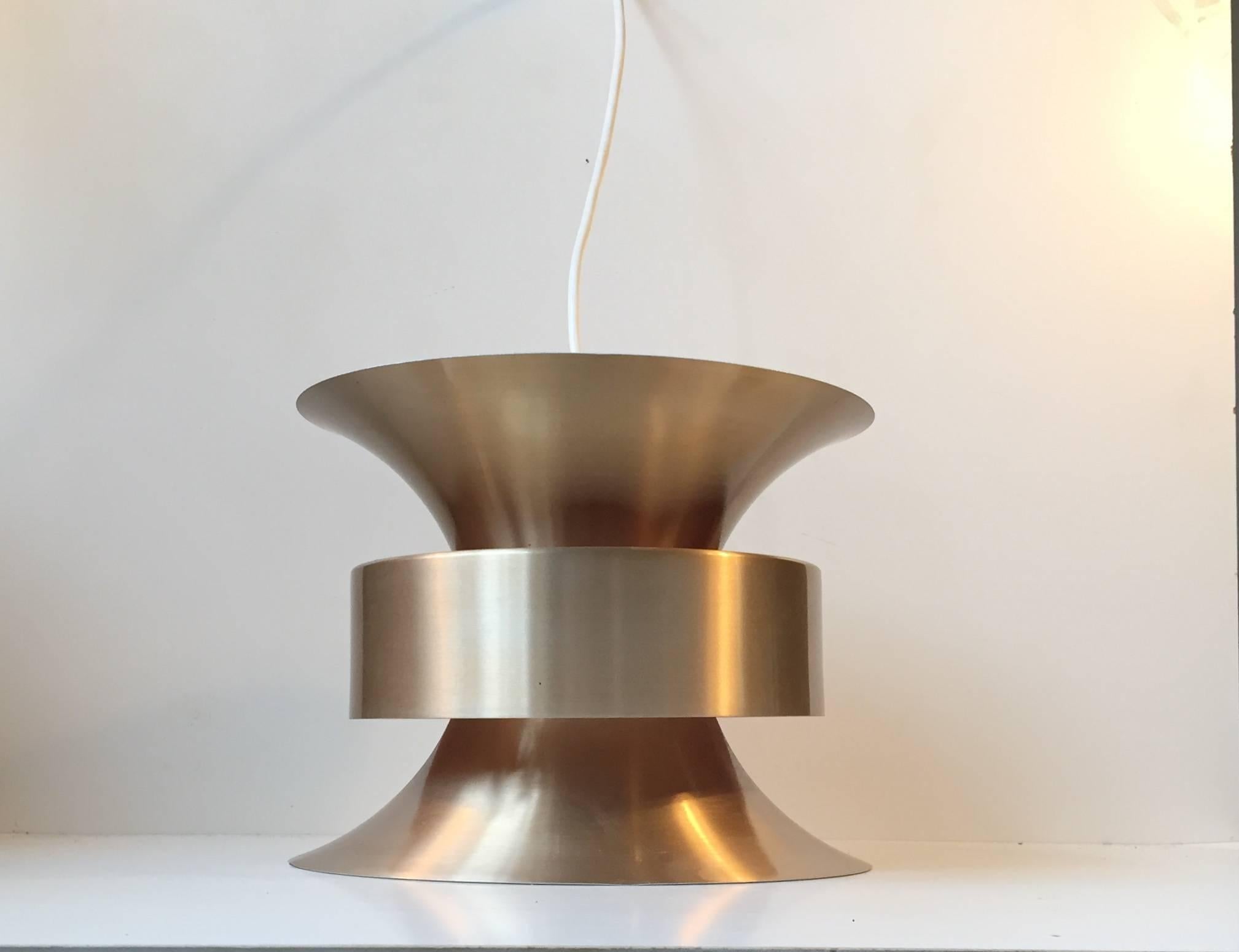 This pendant light was designed by Bent Nordsted. It was manufactured in the 1960s-1970s and is made from brass-alloy aluminum, and has orange and white reflective inner shades. This style of lamp corresponds stylistically with design by Carl Thore