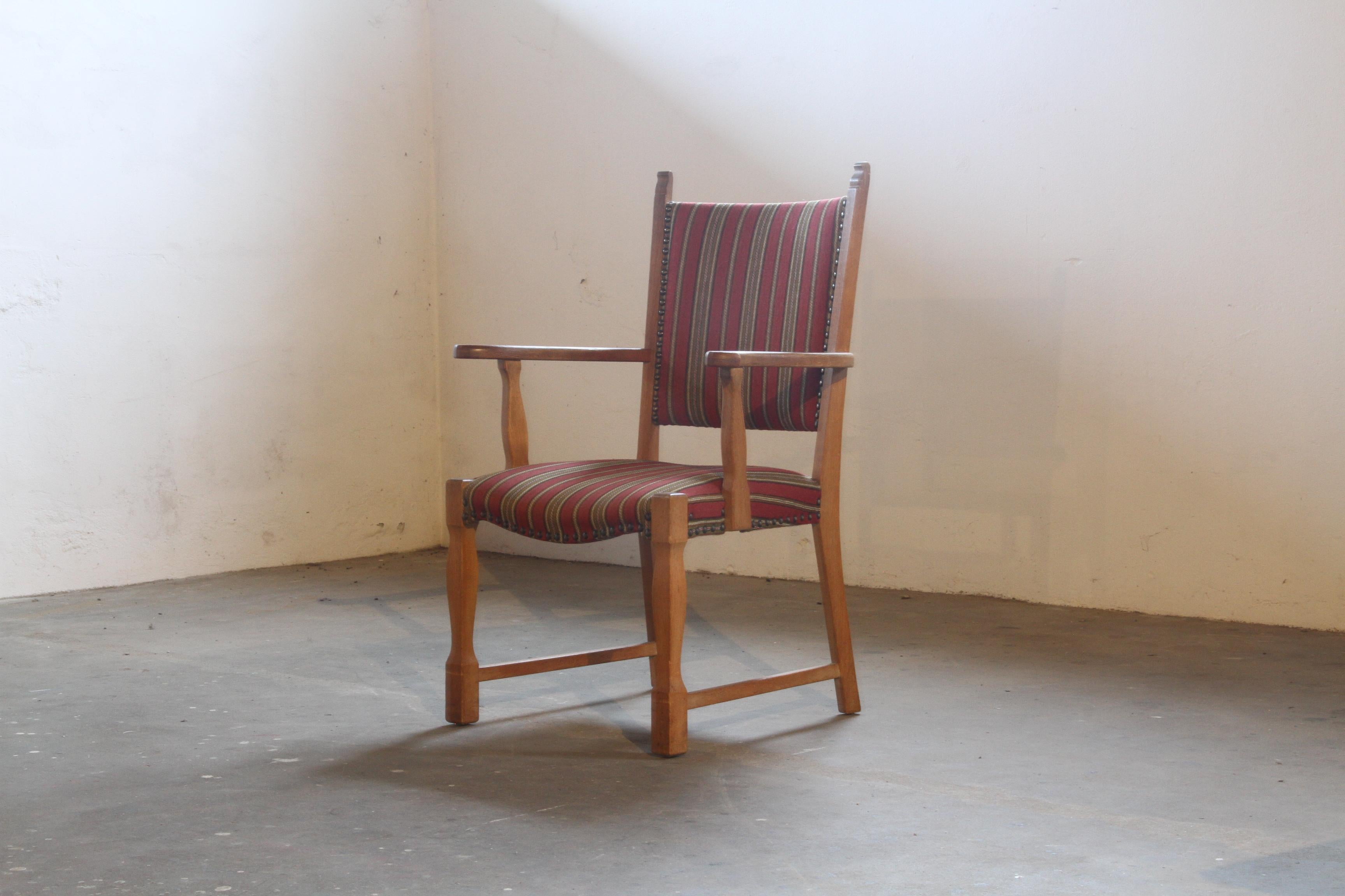 Una splendida poltrona in quercia nello stile di Henning Kjaernulf, che sfoggia un audace design brutalista con una silhouette unica a forma di trono. Ispirato al famoso designer danese, questo pezzo è in condizioni originali, con il tessuto e la