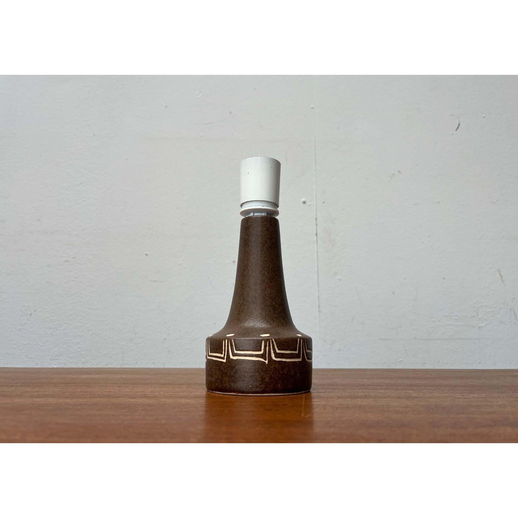 Un design tradizionale. La semplice base in ceramica ha un colore di base marrone ed è decorata con fini ornamenti bianchi. In commercio si possono trovare ombrelli a pinza abbinati.
La lampada è in ottime condizioni con segni di usura e patina.
Il