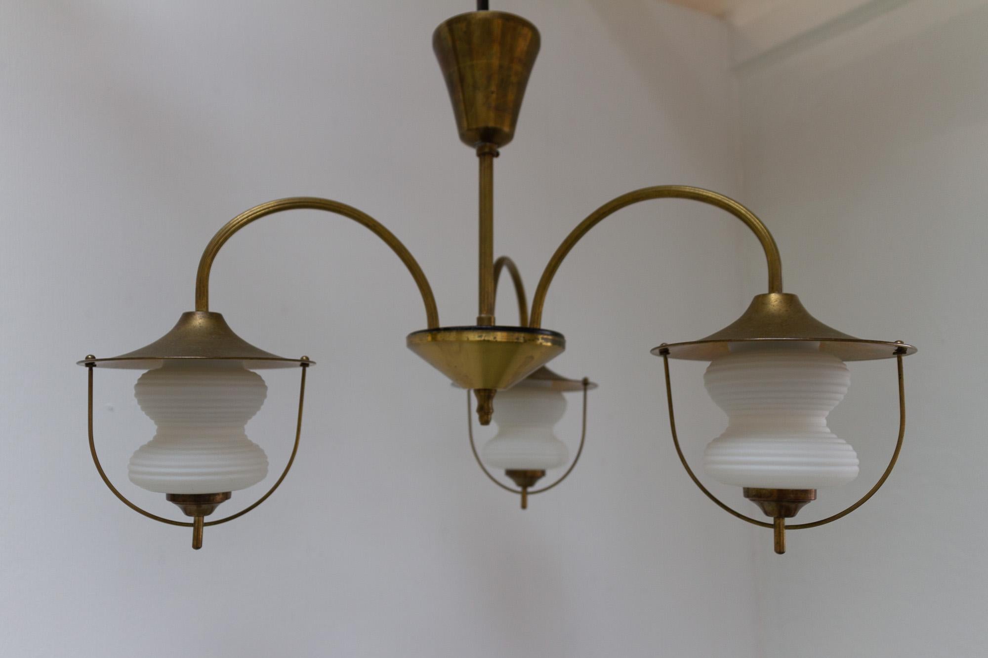 Vintage Danish Chandelier in Opal Glass and Brass, 1950s.
Mid-century modern Scandinavian ceiling lamp in beautifully patinated brass and three opaline glass shades suspended in arched arms. 
The three peanut/hourglass shaped white glass diffusers