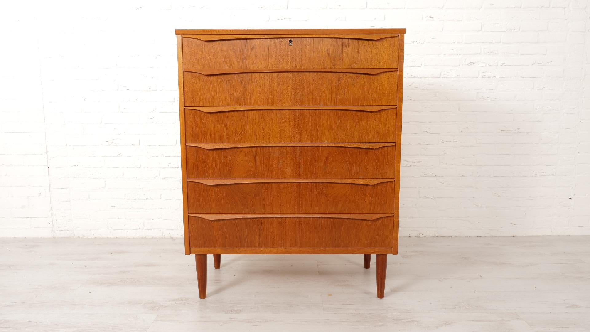 Beautiful vintage chest of drawers, from Denmark. The chest offers a lot of practical storage space and has a crazy look thanks to the beautiful colour of the teak and the subtle wooden handles on the drawers. The chest of drawers has 6