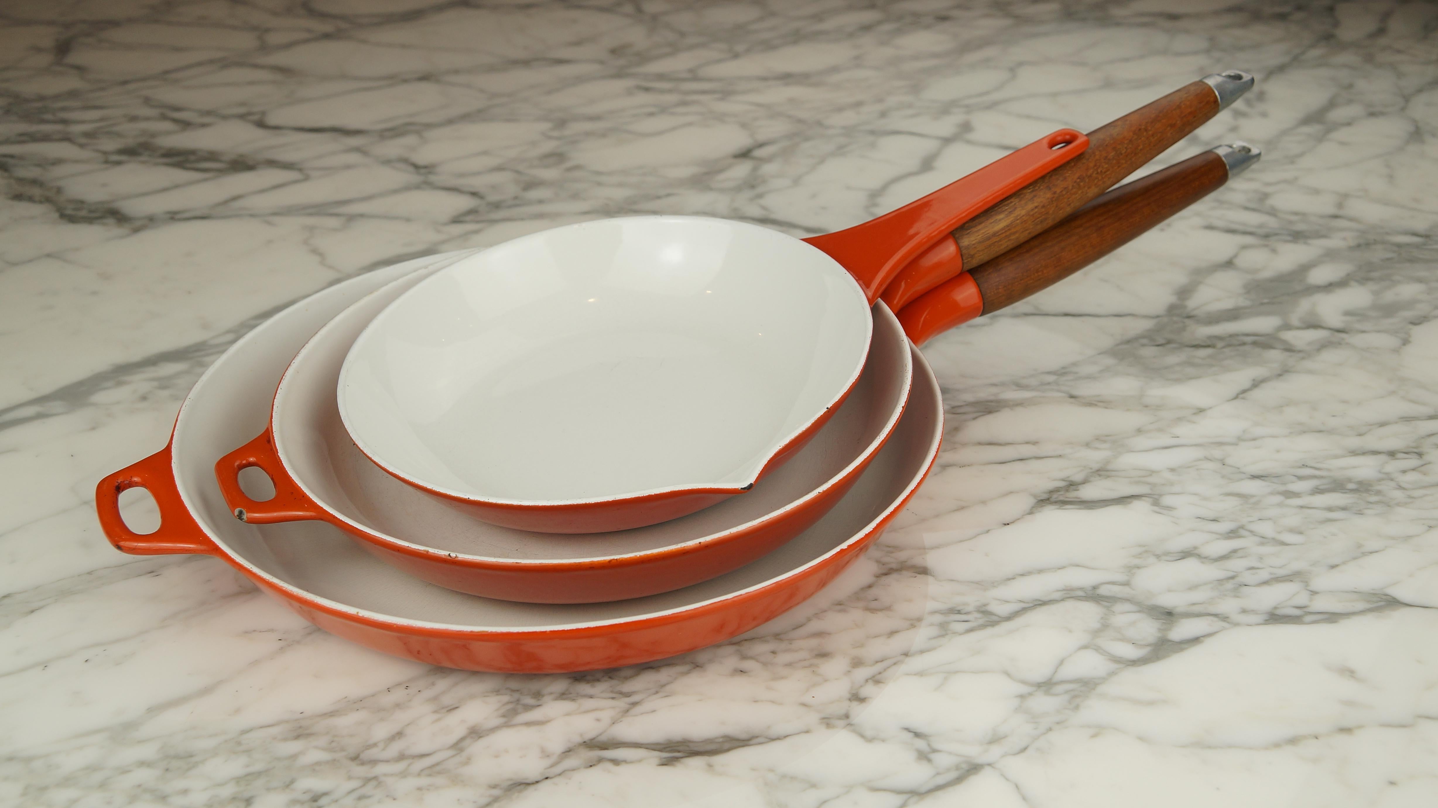 Rare set of vintage Danish Copco orange and white enamel cast iron pans with teak wood handles - designed by Michael Lax.

A stunning trio of enamel cast iron pans or skillets designed by Michael Lax for Copco Denmark in the 1960s.

These will