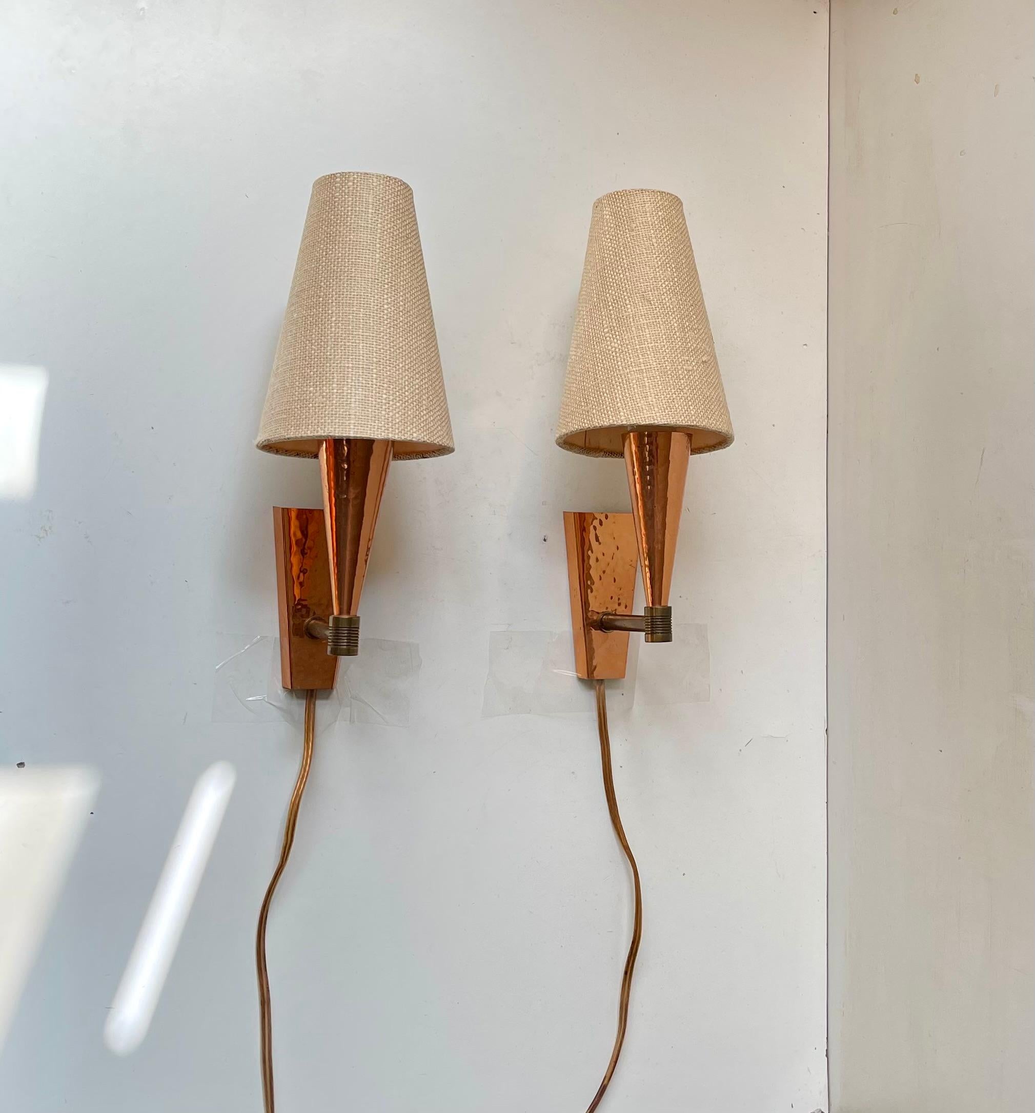Una coppia di applique fisse progettate da Svend Mejlstrøm in Danimarca negli anni '60 e realizzate da MS Belysning. Il set è realizzato in rame martellato e viene fornito con paralumi d'epoca in tessuto di hessian. 

Misure: H: 28 cm, Diametro: 15
