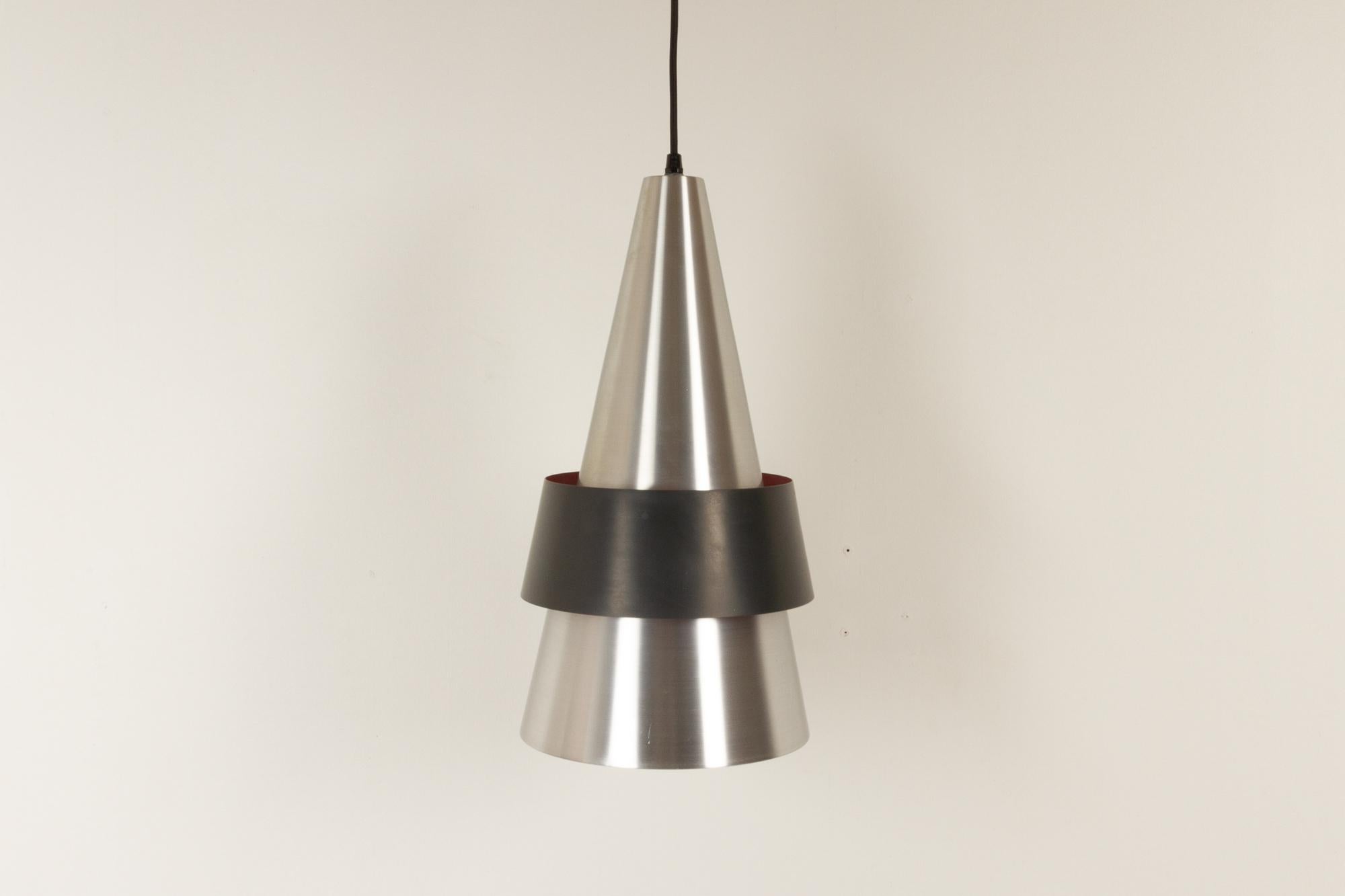 Vintage Danish corona pendant by Jo Hammerborg for Fog & Mørup 1960s
Cone of solid satin aluminum, filament screened by girdle of iron, outside black lacquered, inside light cyclamen.
The Corona pendant gives a characteristic decorative light