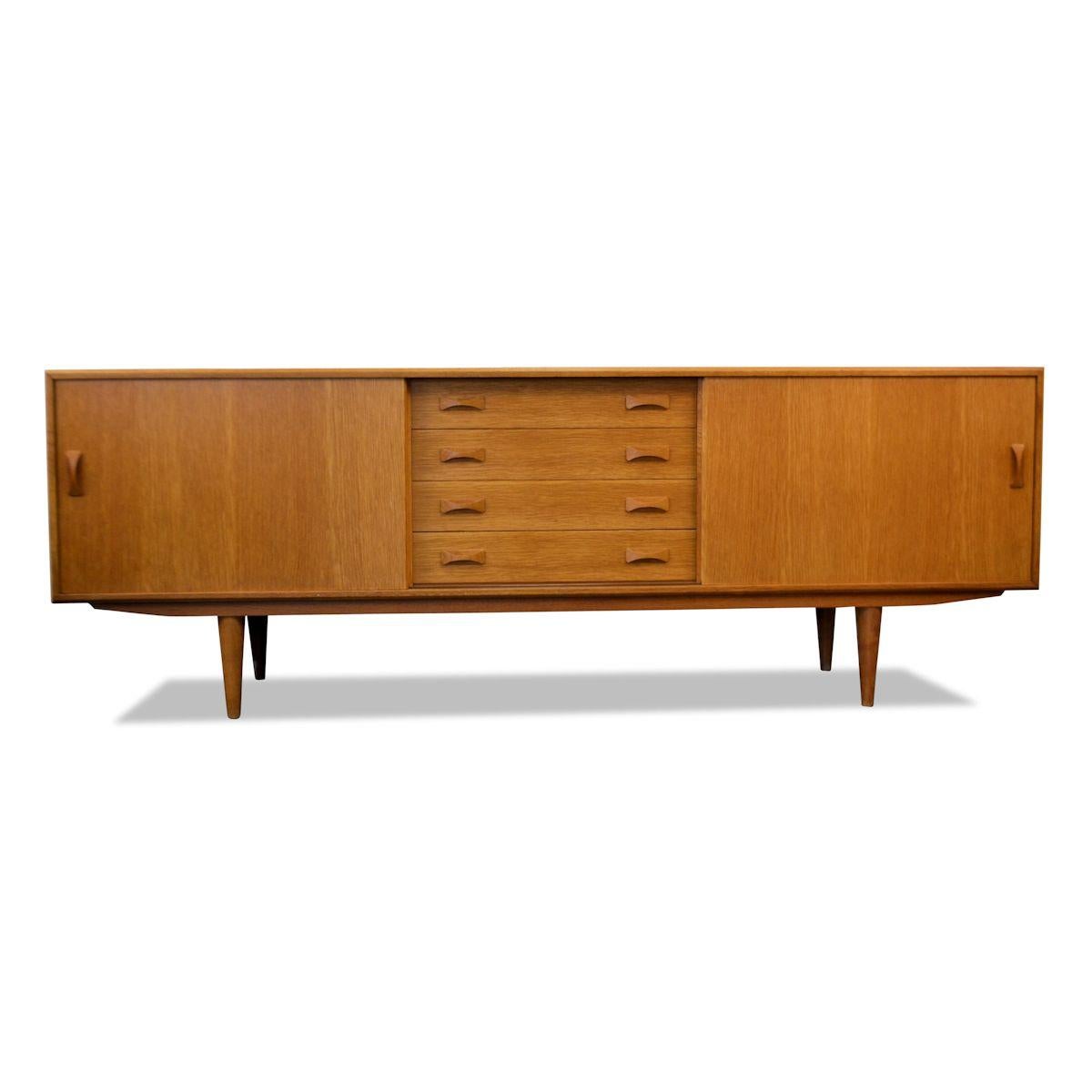 Midcentury sideboard designed and manufactured by Danish maker Clausen and Son. This simple yet sophisticated symetrical sideboard features a typical Danish Modern design. Gorgeous oakwood, stylish door and drawer handles and offerss ample storage