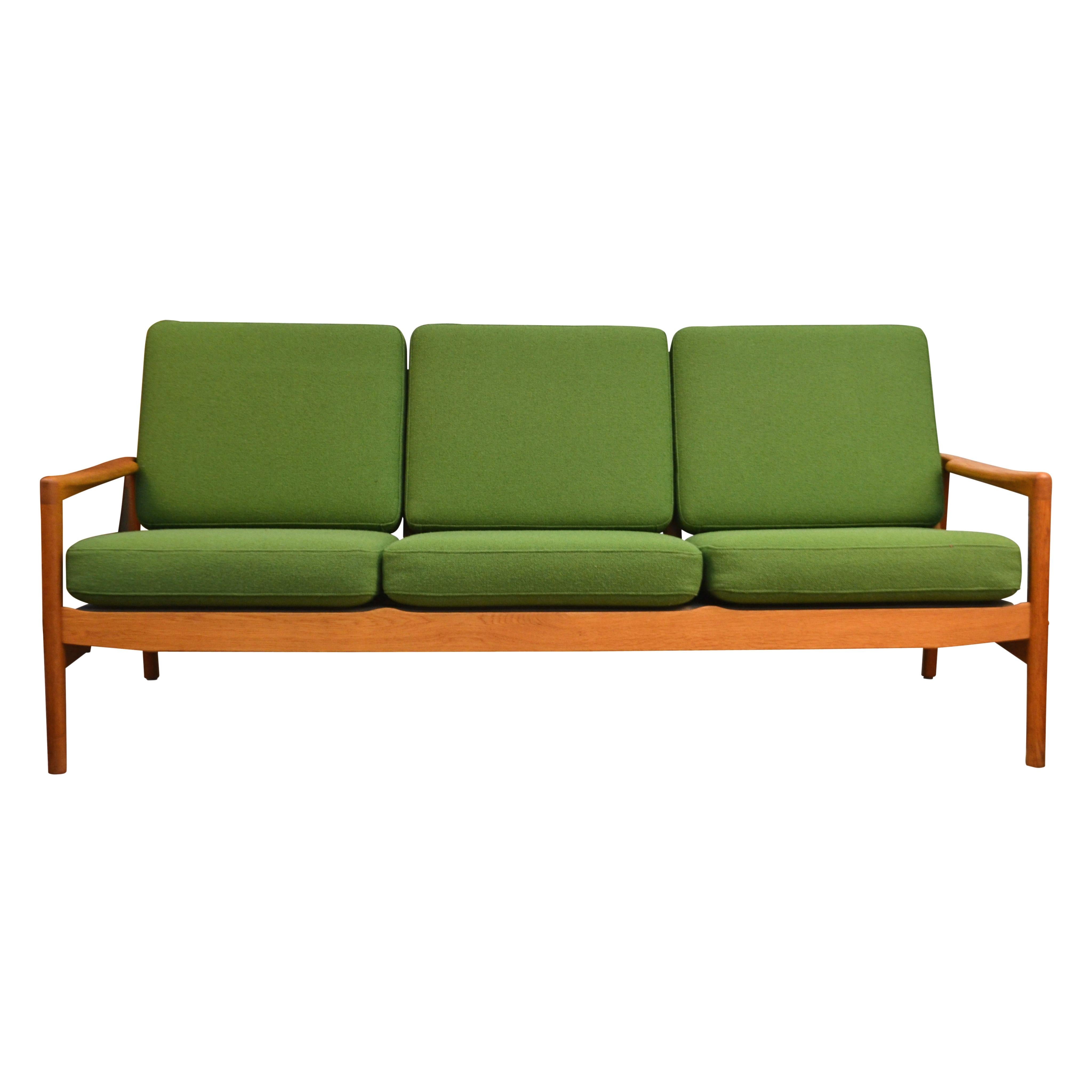 Stunning vintage three-seater sofa designed by Danish designer Hans Olsen for Juul Kristensen. This model 563/3 sofa features a stylish 1960s design, beautiful oak wood, gorgeously sculpted armrests, and comfortable seating. The high quality wool