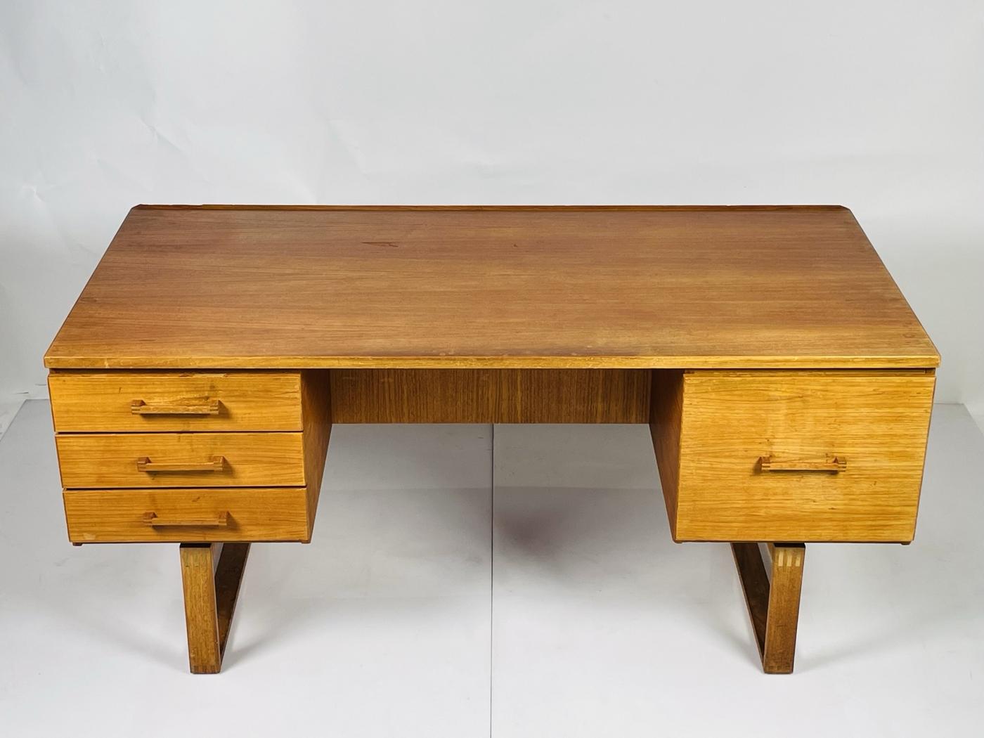 Vintage desk made in Denmark by Henning Jensen and Torben Valeur for Dyrlund. Unique details include two rectangular bases, which gives the desk a floating , light appearance. 
There are 4 drawers, positioned 3 on one side of the desk and a large