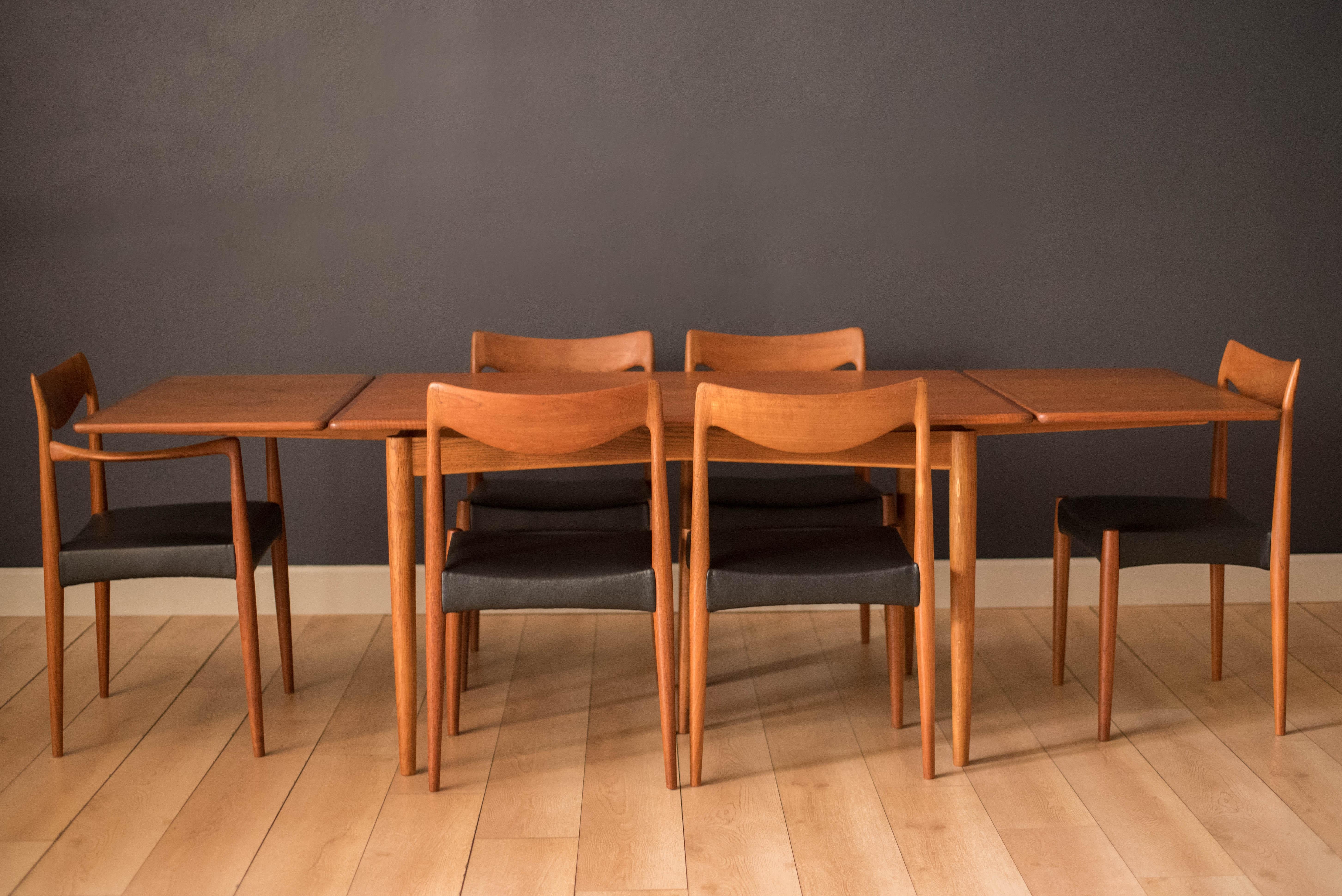 Mid-Century Modern draw leaf dining table in teak, circa 1960s. This rectangular tabletop features continuous flowing grains framed with solid teak edge banding and rounded edges. Supported by a contrasting oak base designed with an angled bow tie