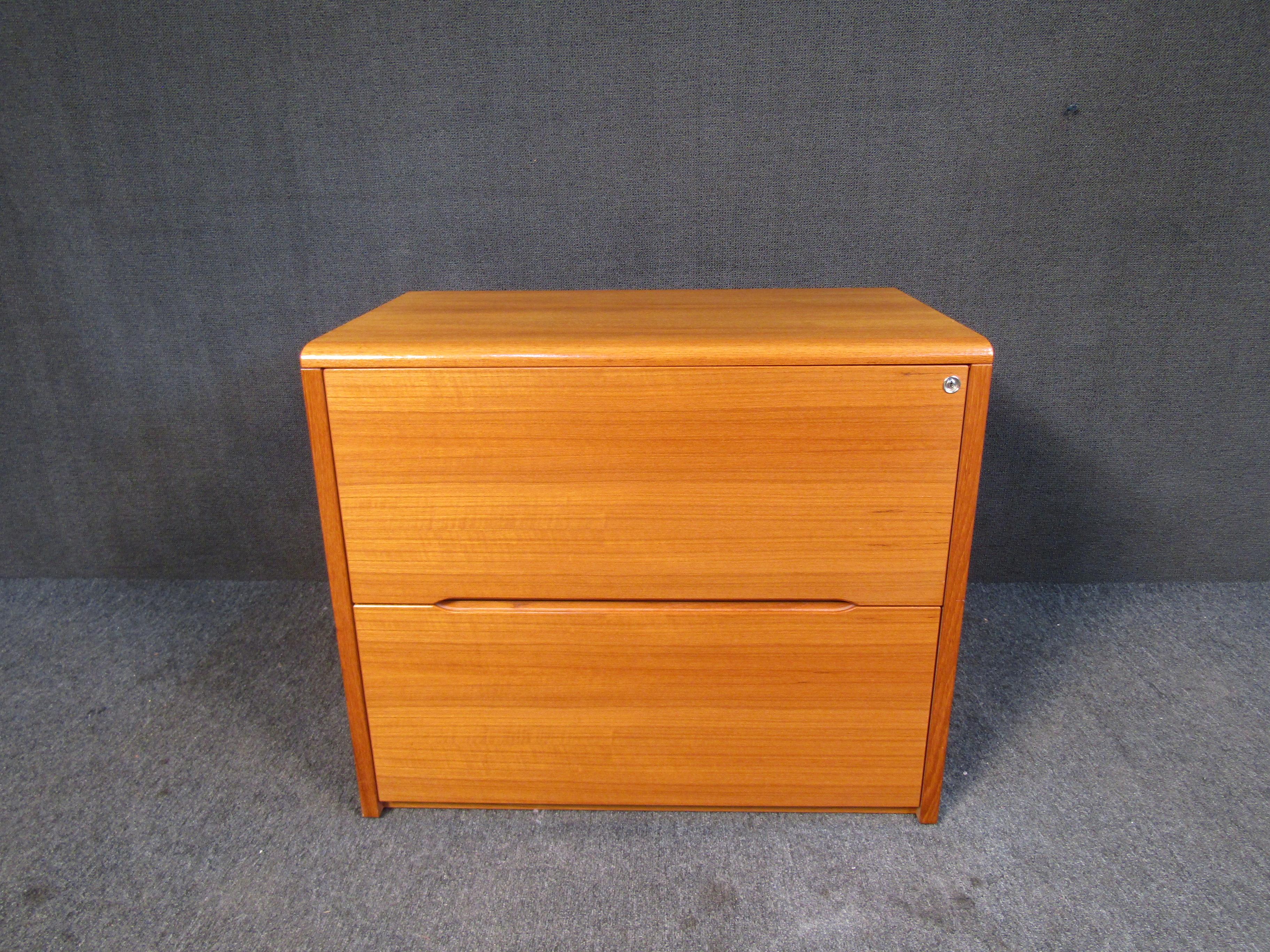 Handsome vintage Danish Modern filing cabinet. This piece features teak woodgrain, inset handles, a locking mechanism w/ keys and plenty of storage for all of your filing needs. Please confirm item location with seller (NY/NJ).