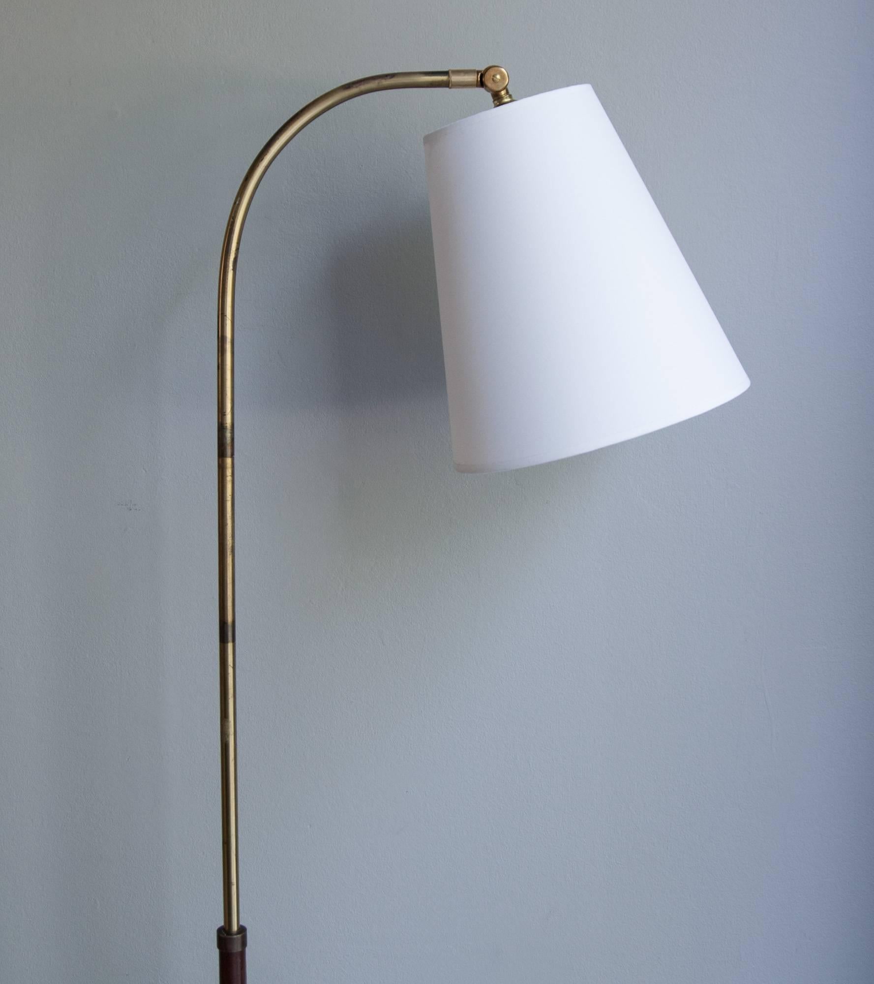 Vintage leather and brass floor light, Denmark, 1940s.
With a circular base in polished brass, the lamp has the stem covered in hand-sewn brown leather with white seams.
Adjustable in height from 140 to 180cm, the lamp has a newly made shade in