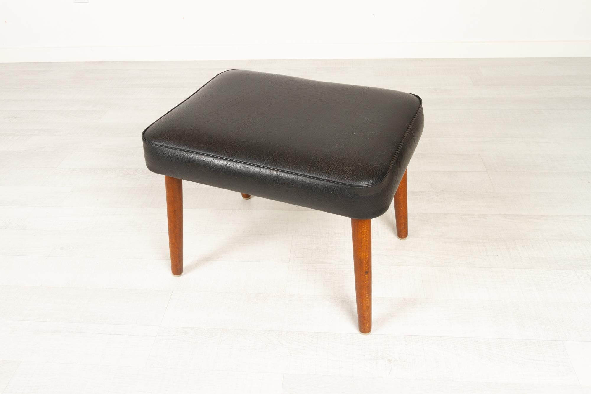 Vintage danish teak footstool 1960s
Danish Mid-Century Modern stool with round tapered legs in solid stained beech. Original upholstery in black leatherette. 
Elegant and handy little footrest with thick upholstery.
Very good original condition.