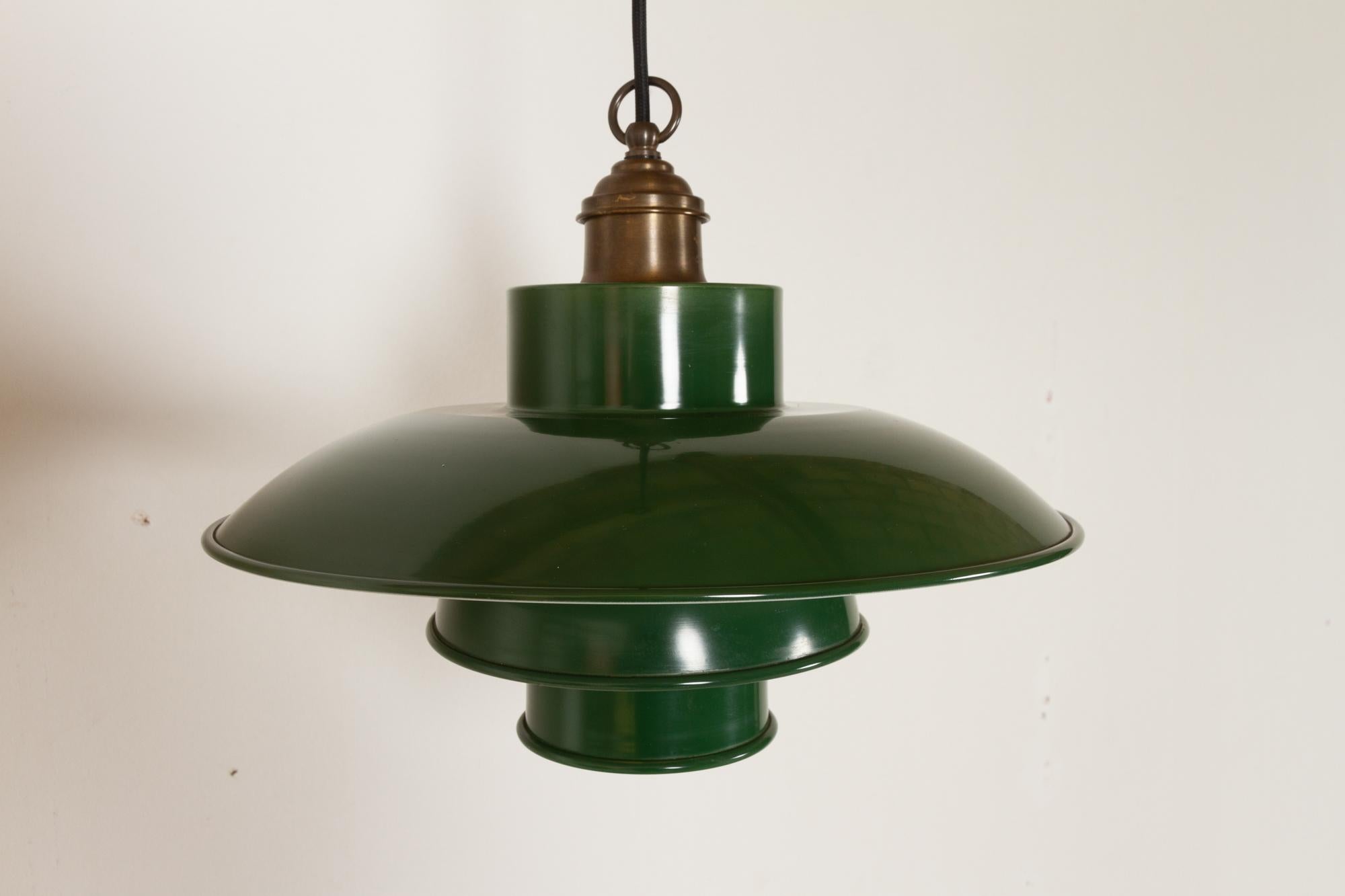 Vintage Danish green pendant 1960s
Classic Danish Mid-Century Modern ceiling pendant in green enamelled metal. Three shades with white undersides disperses the light in all directions without blinding. Top in patinated brass. 
E26/27 socket. 220