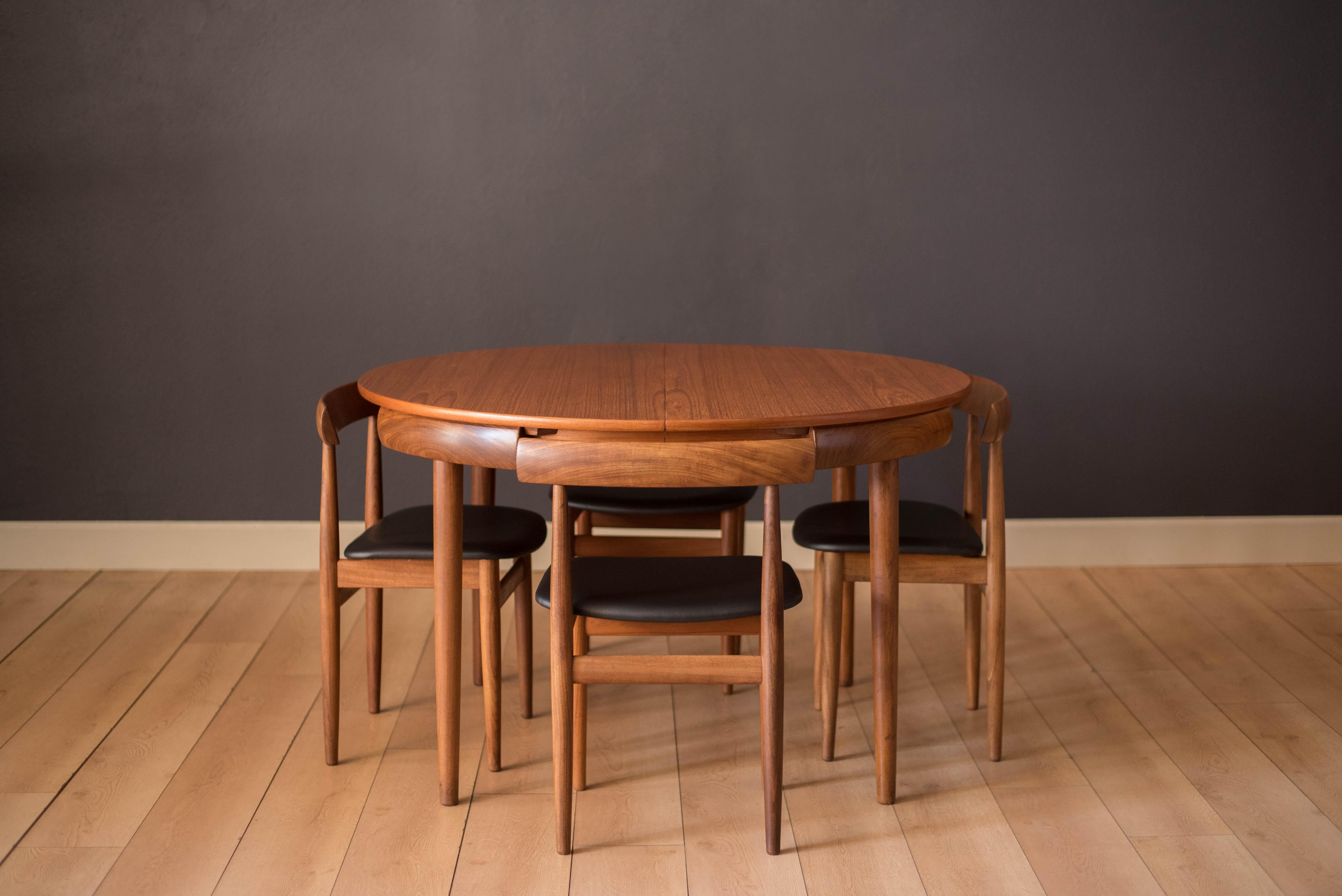 Mid century round dining set designed by Hans Olsen for Frem Rojle in teak. This compact set includes four chairs that cleverly nest into the table. These dining chairs are the four legged version and seats have been newly reupholstered in black