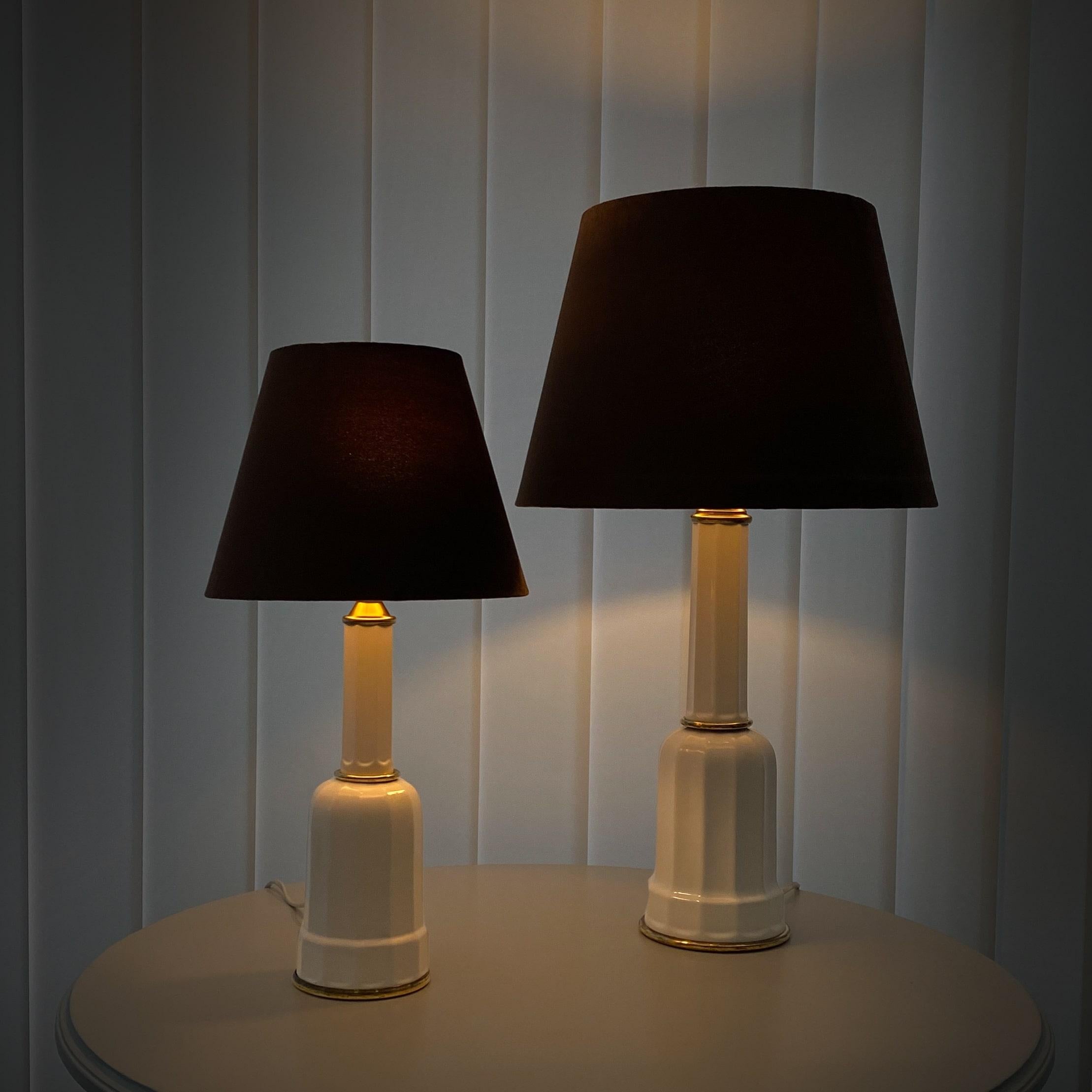 Ein Paar traditioneller dänischer Heiberg-Tischlampen, hergestellt aus Porzellan und Messing. Zwei identische Lampen, aber in zwei verschiedenen Größen. Komplett mit neuen, mit Samt überzogenen Lampenschirmen. Das Modell erhielt seinen Namen nach
