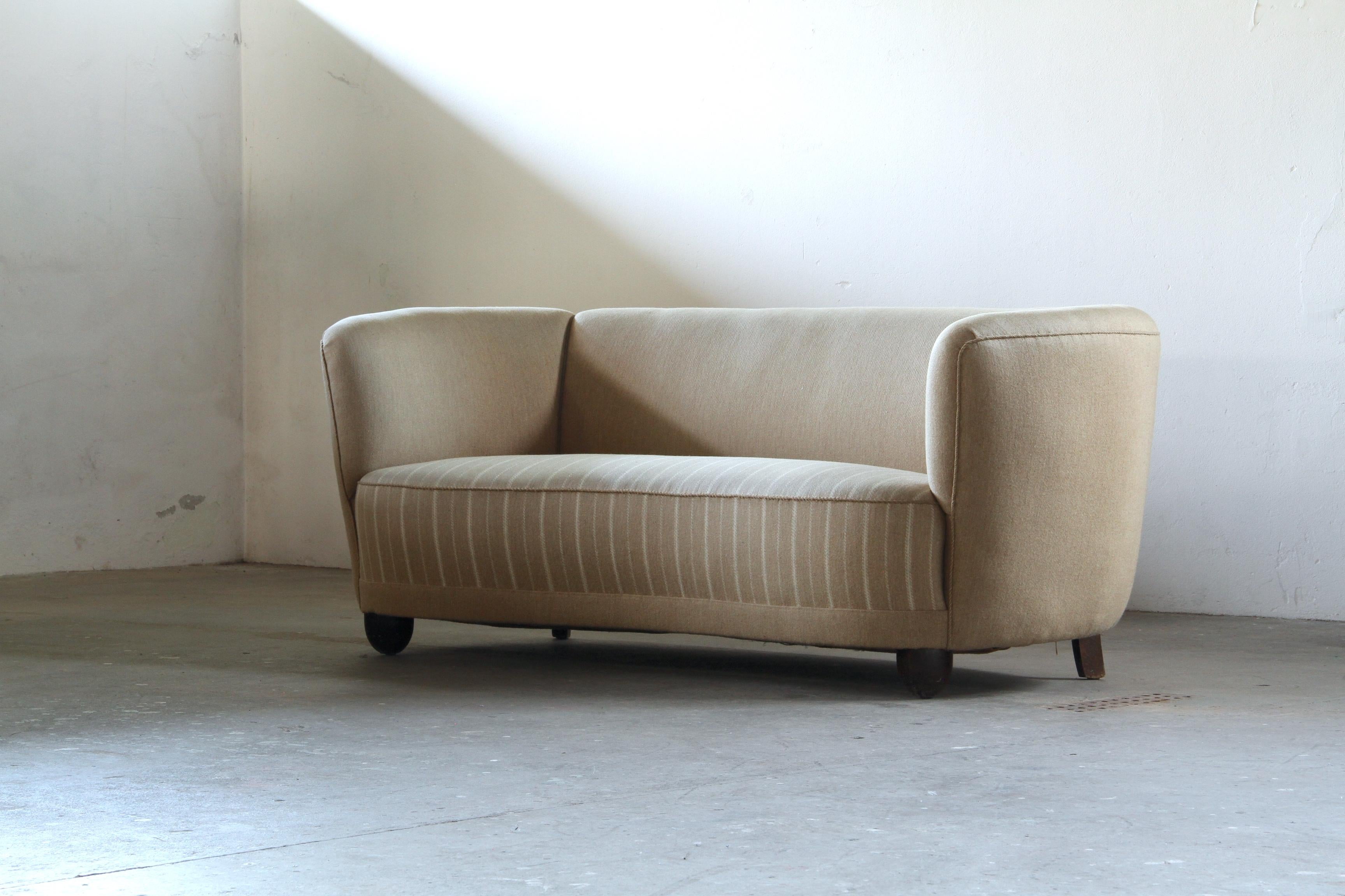 Présentation d'un canapé iconique et sculptural en forme de banane, chef-d'œuvre de l'ébénisterie danoise des années 1940. Ce canapé incurvé incarne l'esprit novateur du design du milieu du siècle, où les lignes organiques et fluides rencontrent une