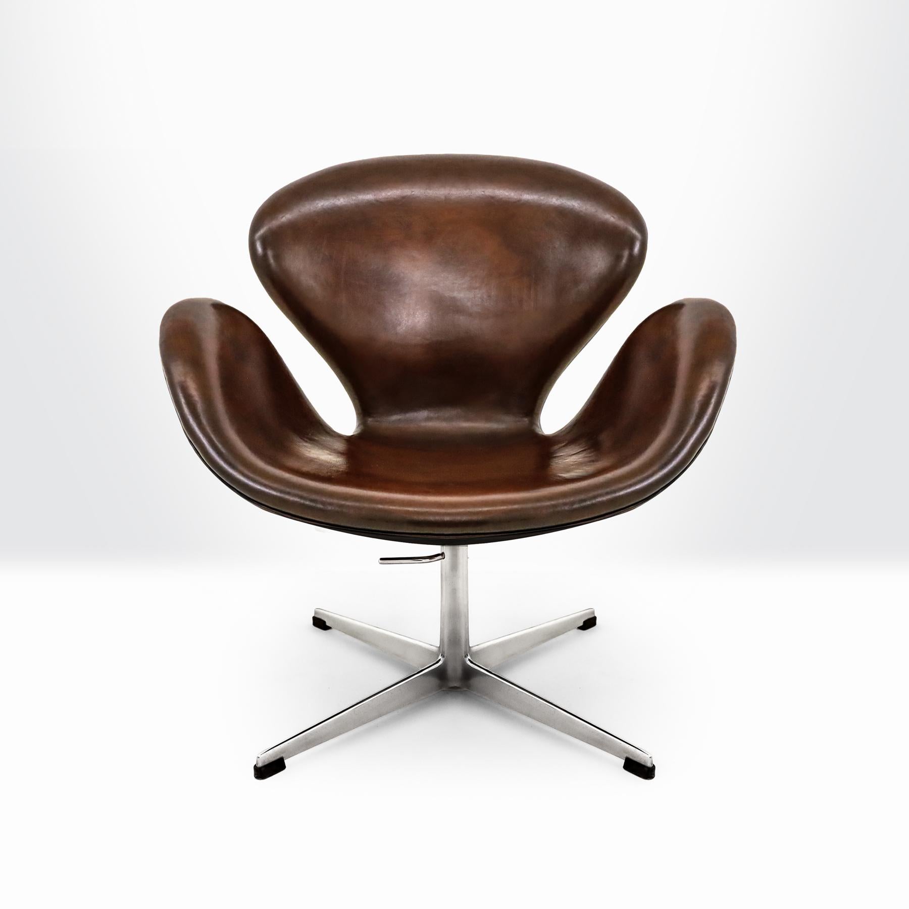 Vintage Danish Mid century 1960s Arne Jacobsen, Fritz Hansen Swan chair in beautifully patinated brown leather with a swiveling, height adjustable, aluminum base.
 
This is possibly one of the most beautifully finished and patinated versions of