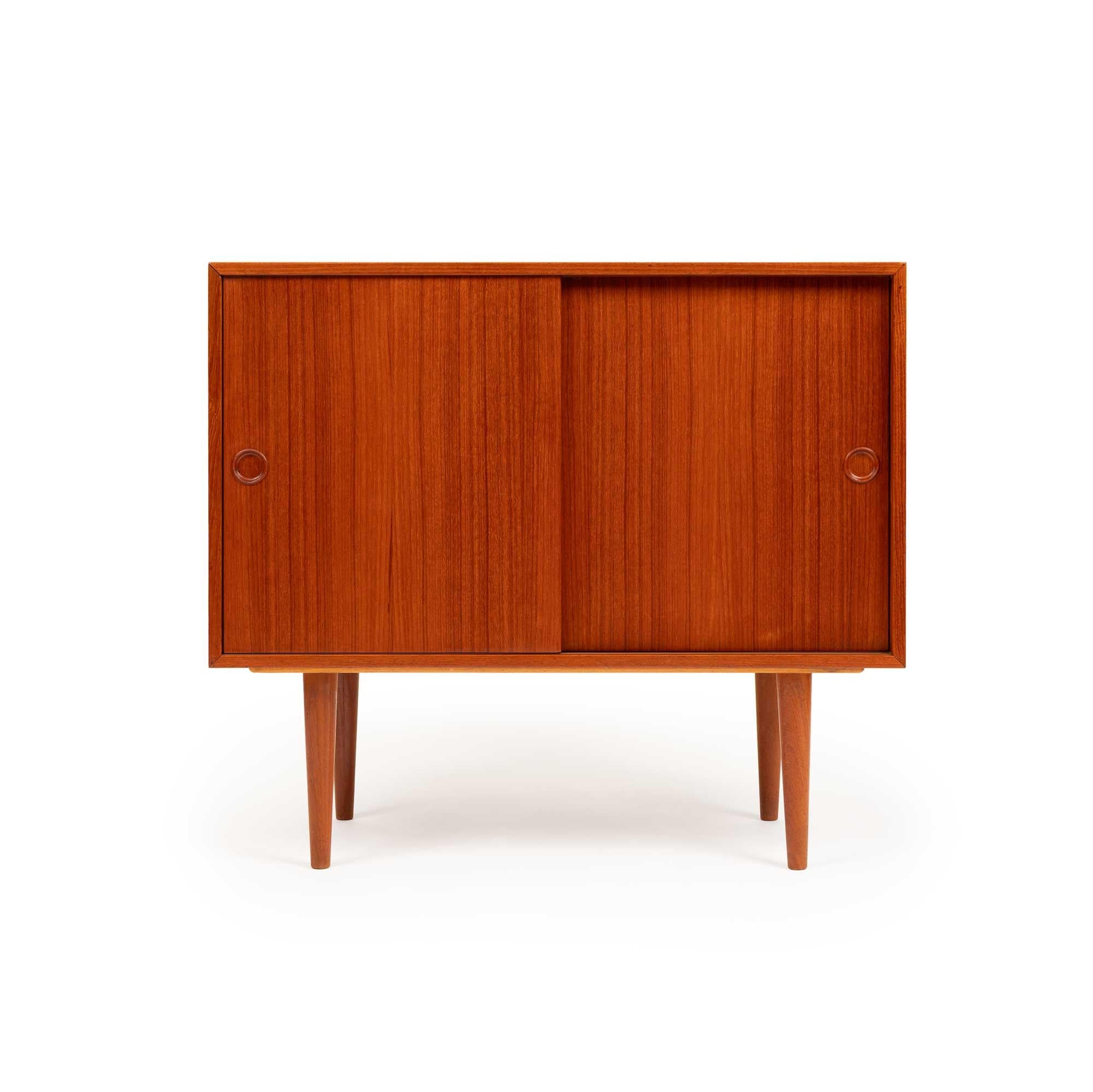 Diese exquisite Teakholz-Credenza im Vintage-Stil von Kai Kristiansen aus der dänischen Mitte des Jahrhunderts zeichnet sich durch eine elegante Teakholzmaserung aus, die durch geschnitzte Griffe ergänzt wird. Die Anrichte ist mit zwei Schiebetüren