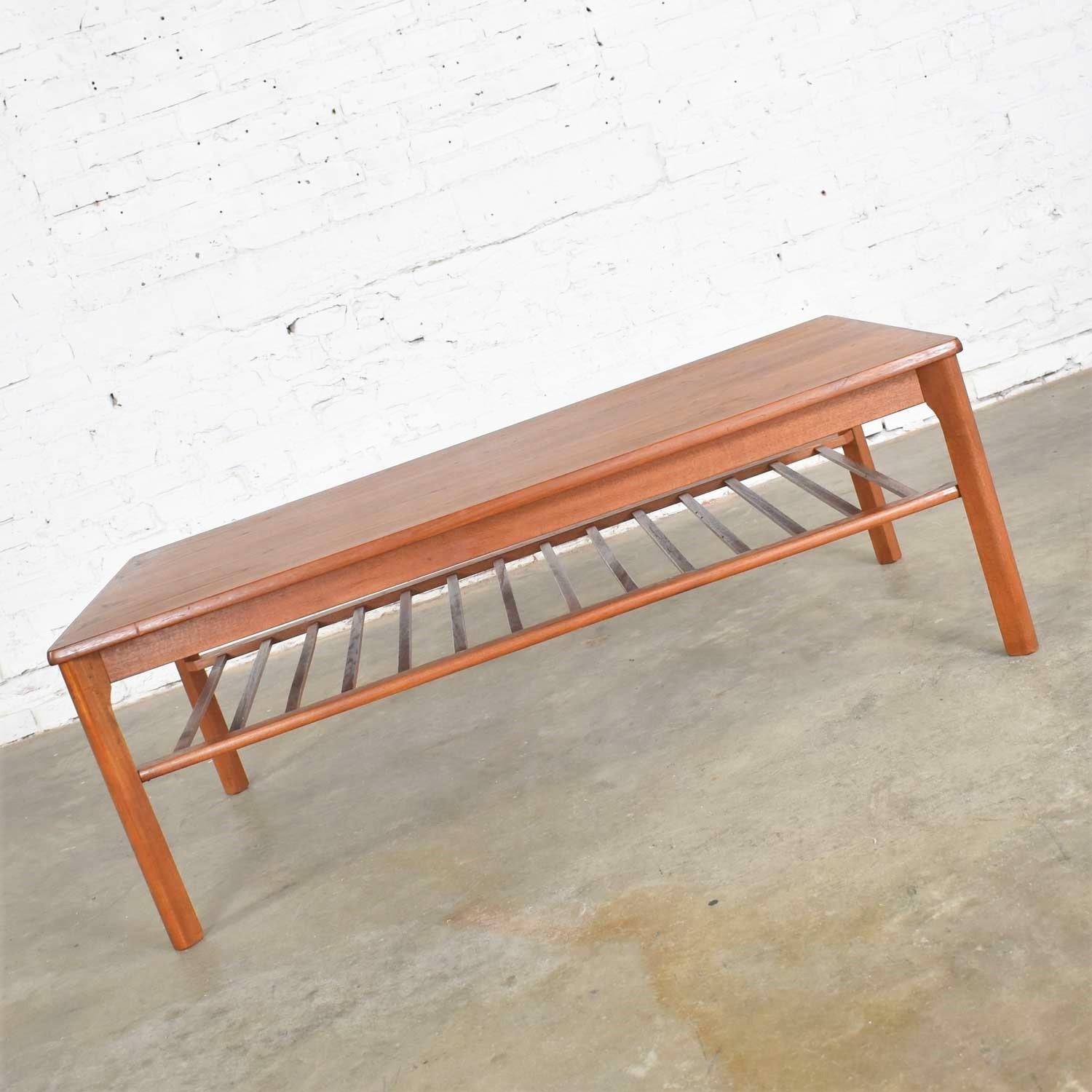 Great vintage Danish modern teak coffee table marked on the bottom Made in Denmark by Mobelfabrikken Toften. It is in beautiful vintage condition. It has had a small repair on one leg and one of the slats on its bottom shelf has been restored by our