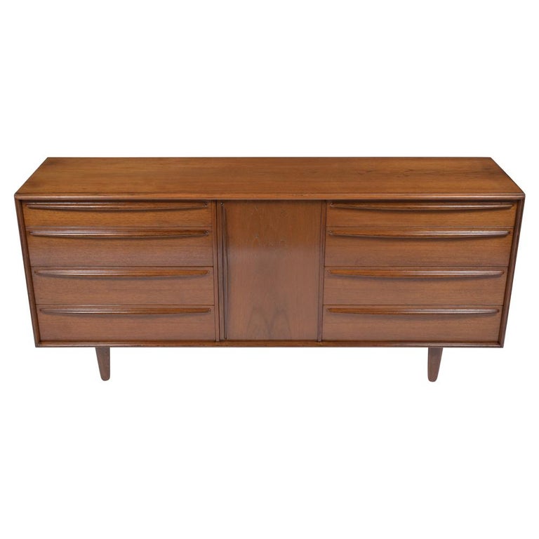 A 1960s mid-century modern danish credenza that has been fully restored, is made out of walnut with stained in a rich walnut color with a semi-gloss lacquered finish. This fabulous sideboard features four pull-out drawers on each side, top two