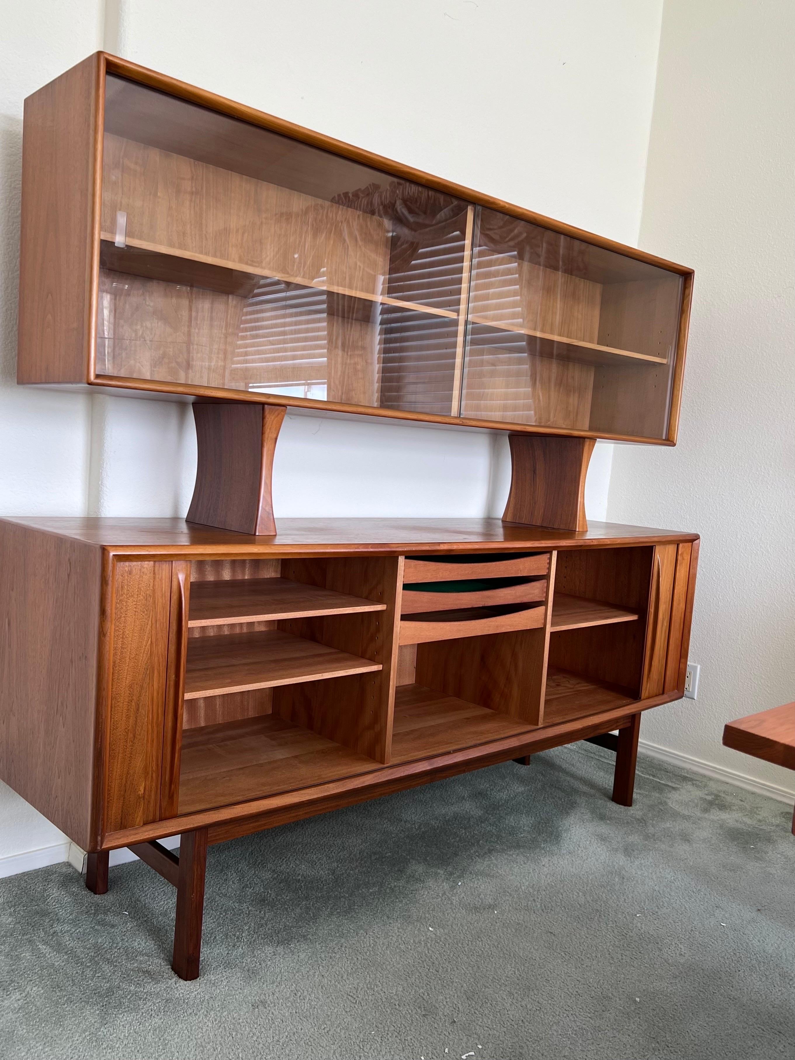 A Mid-Century Modern Danish cabinet and buffet with finish back. This could used as a room divider. The teak buffet with tambour doors conceals shelved storage and the center compartment with three felt lined drawers. The teak china cabinet with two