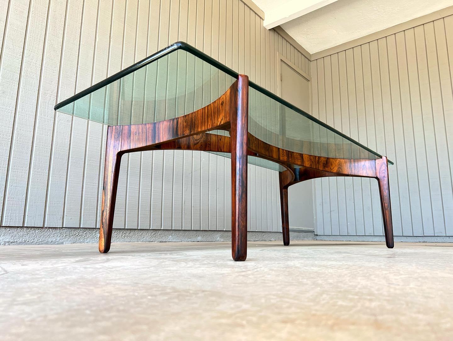 Rosewood base with a glass top mid century modern coffee table designed by Sven Ellekaer for Christian Linneberg Møbelfabrik in the early 1960s in Denmark. The sculptural wood base was already in great condition but has been professionally