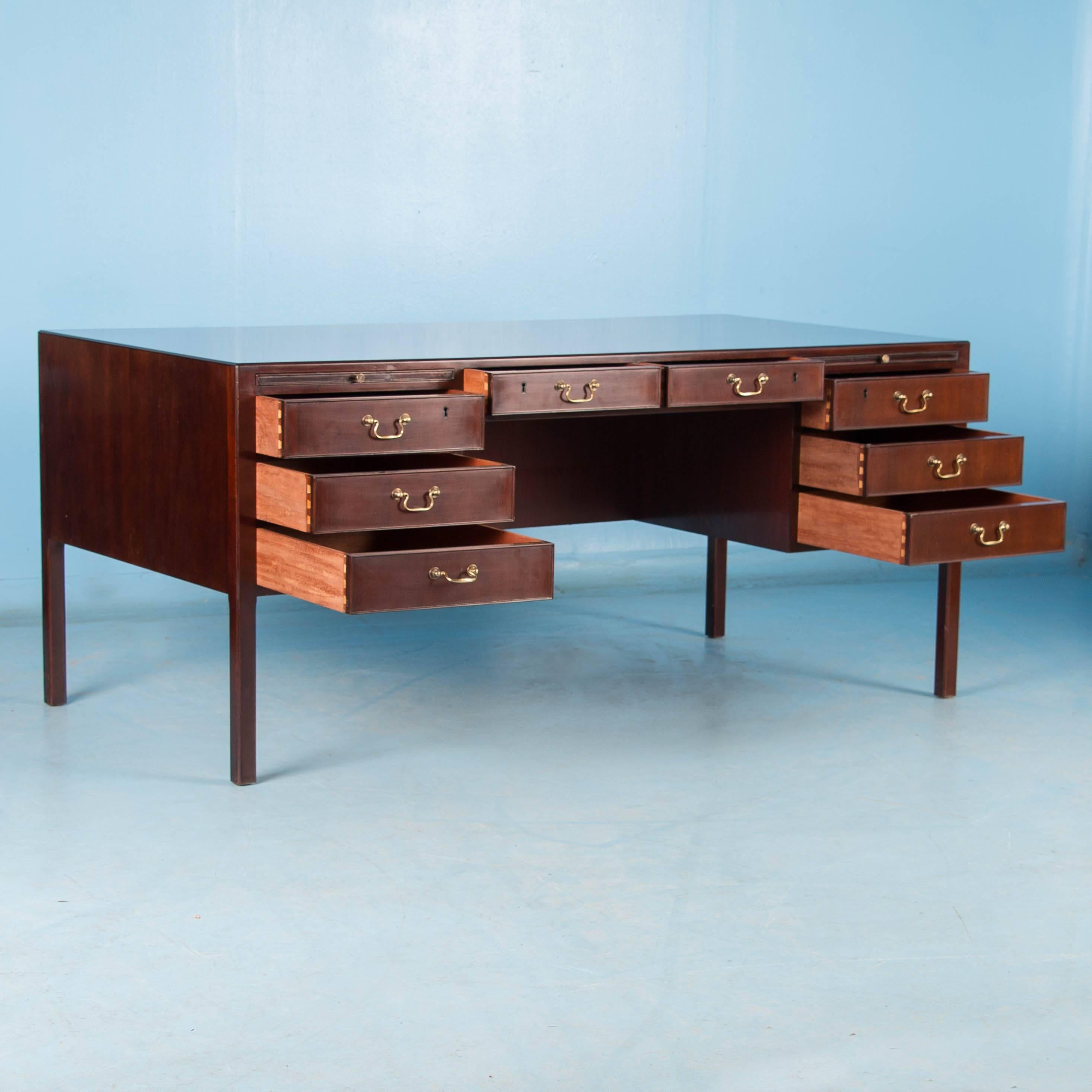 The aged dark red mahogany compliments the clean midcentury style in this free standing desk with locking drawers and original brass pulls. A few unique features are the drawers and drop down cabinet doors on the back. Please take a moment to