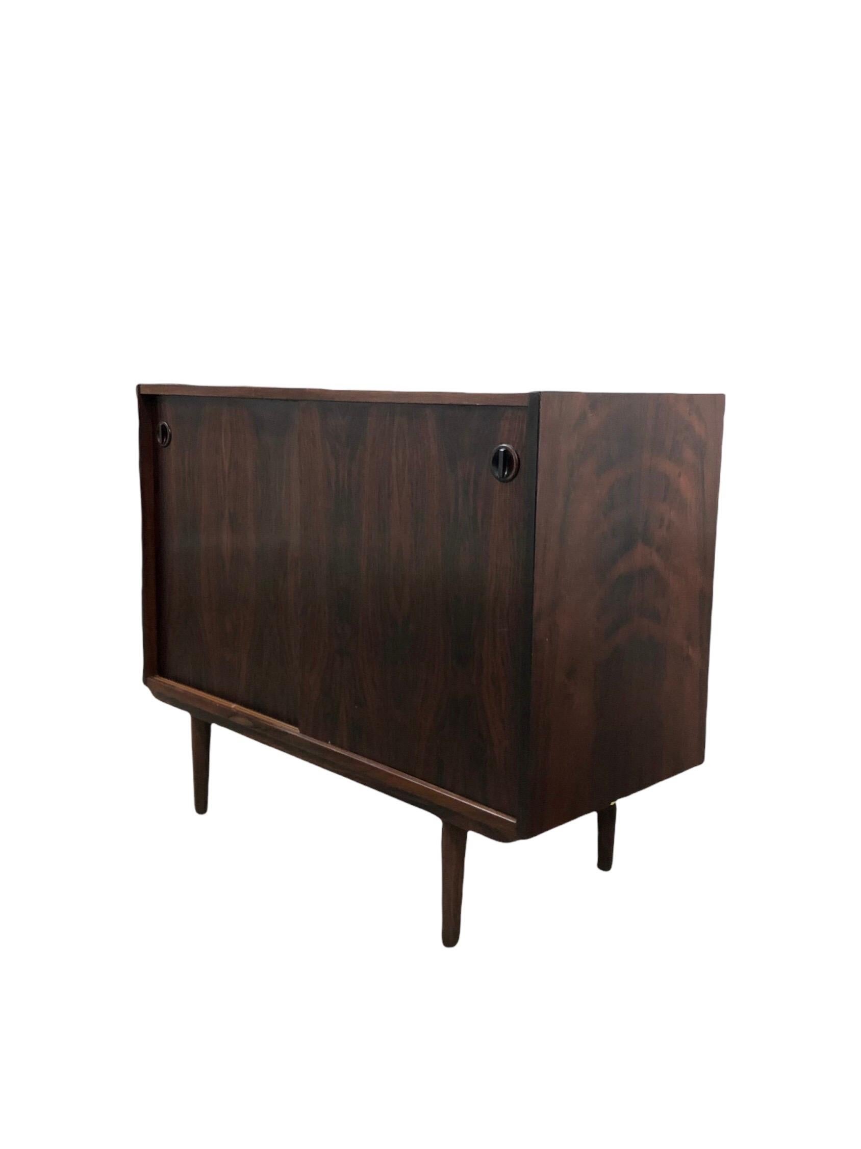 Mid-century Danish Modern rosewood cabinet in style of Kai Kristiansen, manufactured in Denmark with adjustable shelf, with two sliding doors, raised on tapered legs. Cabinet could be use as entry way cabinet or as media cabinet

Dimensions: 39 W