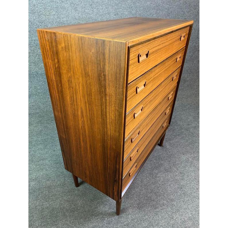 
Here is a beautiful Scandinavian Modern highboy dresser in rosewood manufactured by Munch Møbler Slagelse in Denmark in the 1960s. This dresser, recently imported from Copenhagen to California, features clean design lines and sculpted recess drawer