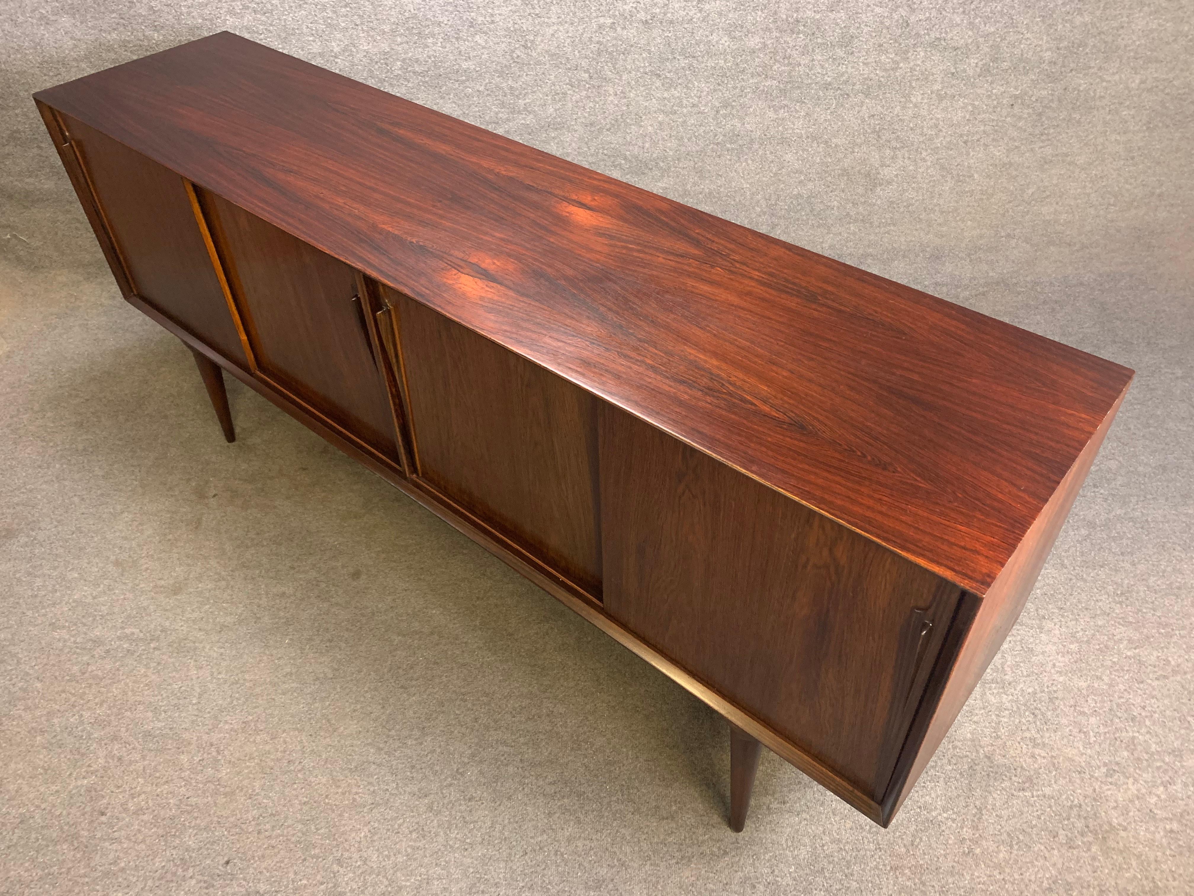 Here's a rare Scandinavian Modern sideboard in rosewood designed by Gunni Omann for Omann Jun Mobelfabrik in Denmark in the 1960s.
This superb credenza features a vibrant wood grain and four sliding doors revealing multiple adjustable shelvings and