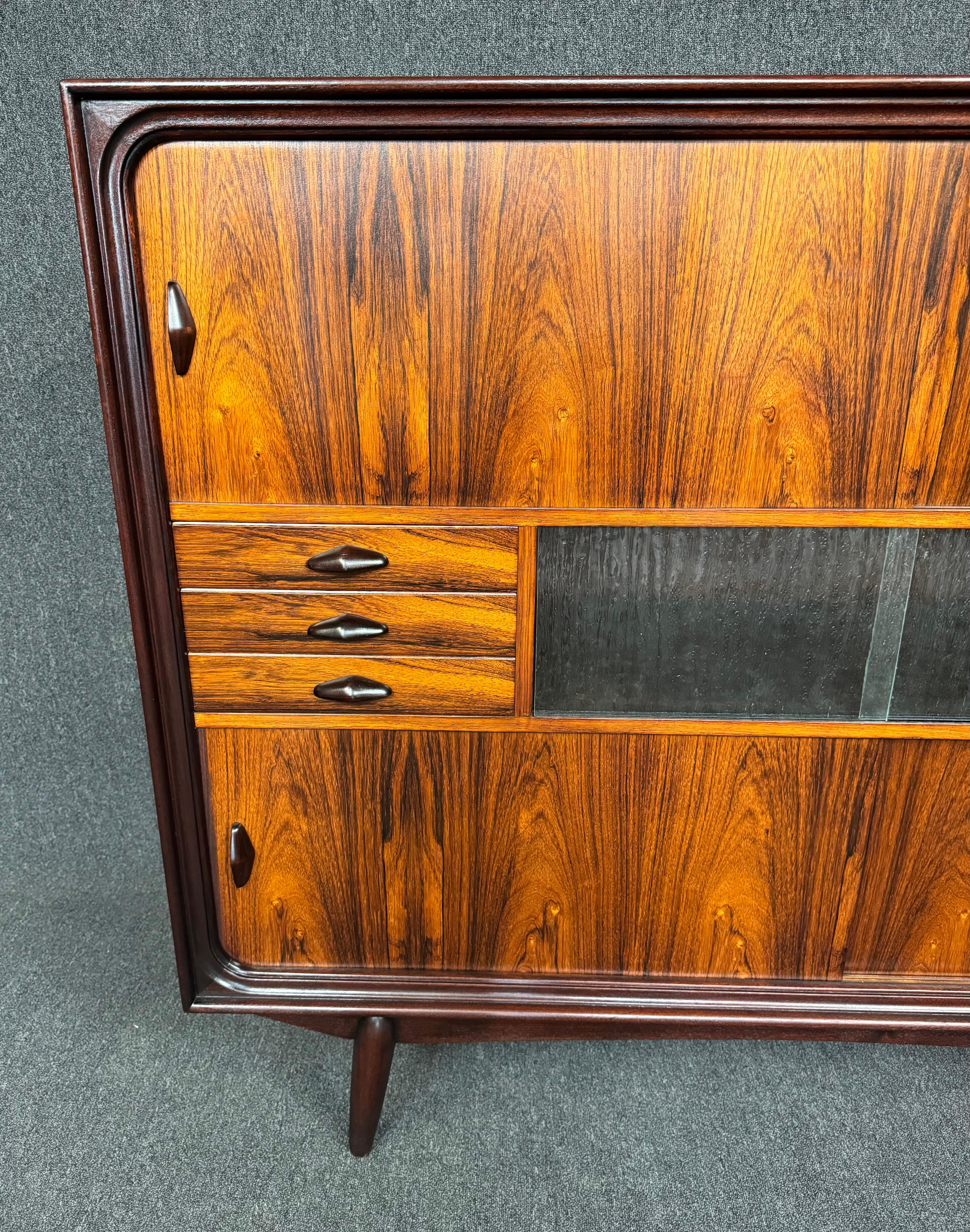 Here is a beautiful scandinavian modern high sideboard in rosewood manufactured in Denmark in the 1960's.
This exquisite case piece, recently imported from Europe to California before its full refinishing, features a vibrant wood grain, multiple