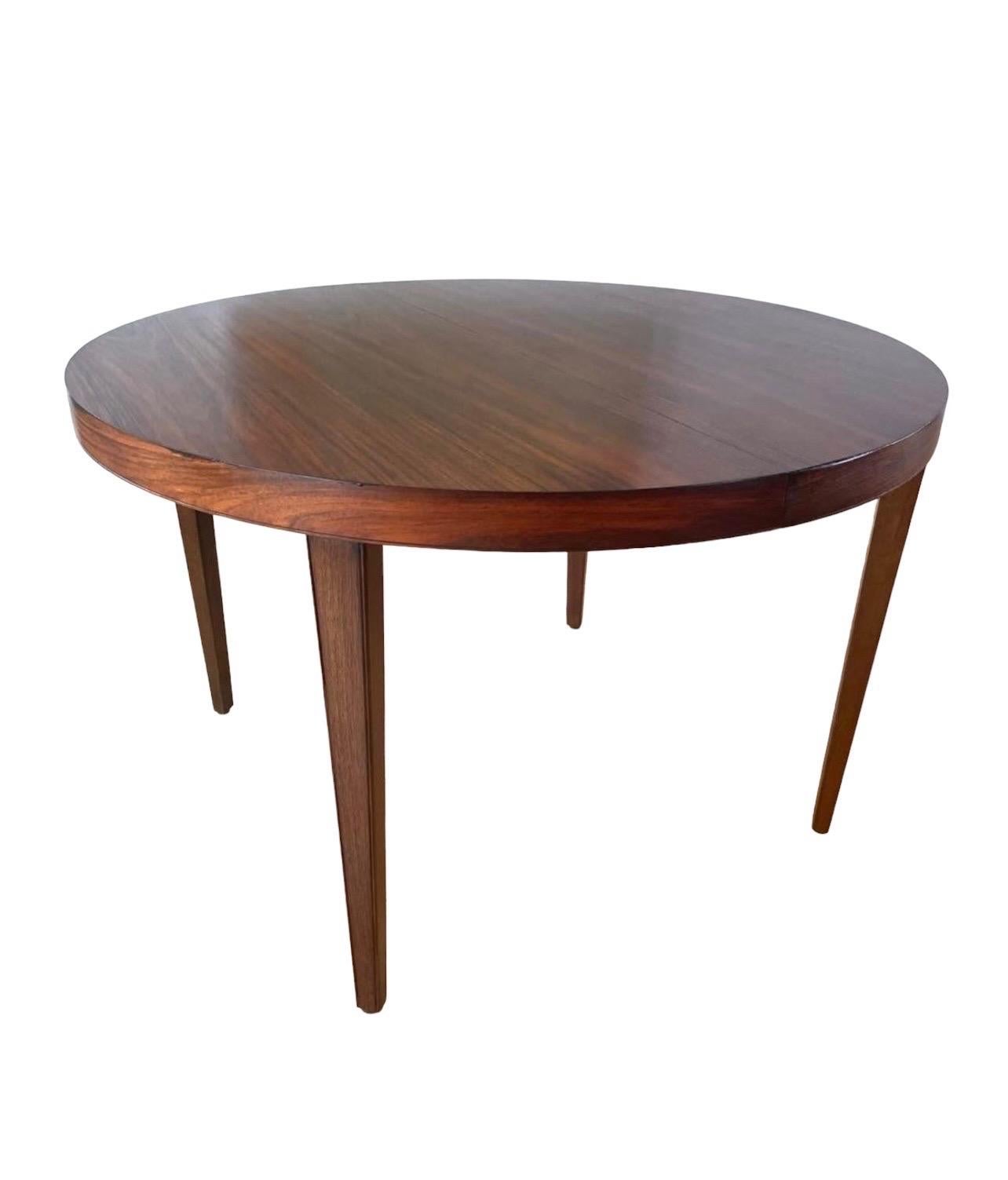This exceptional rosewood dining table from Denmark is in near perfect condition. This table can be round for smaller areas or oval to seat more. Comes with one leaf. Stunning wood grain and original finish. One end of the table has a darkened spot