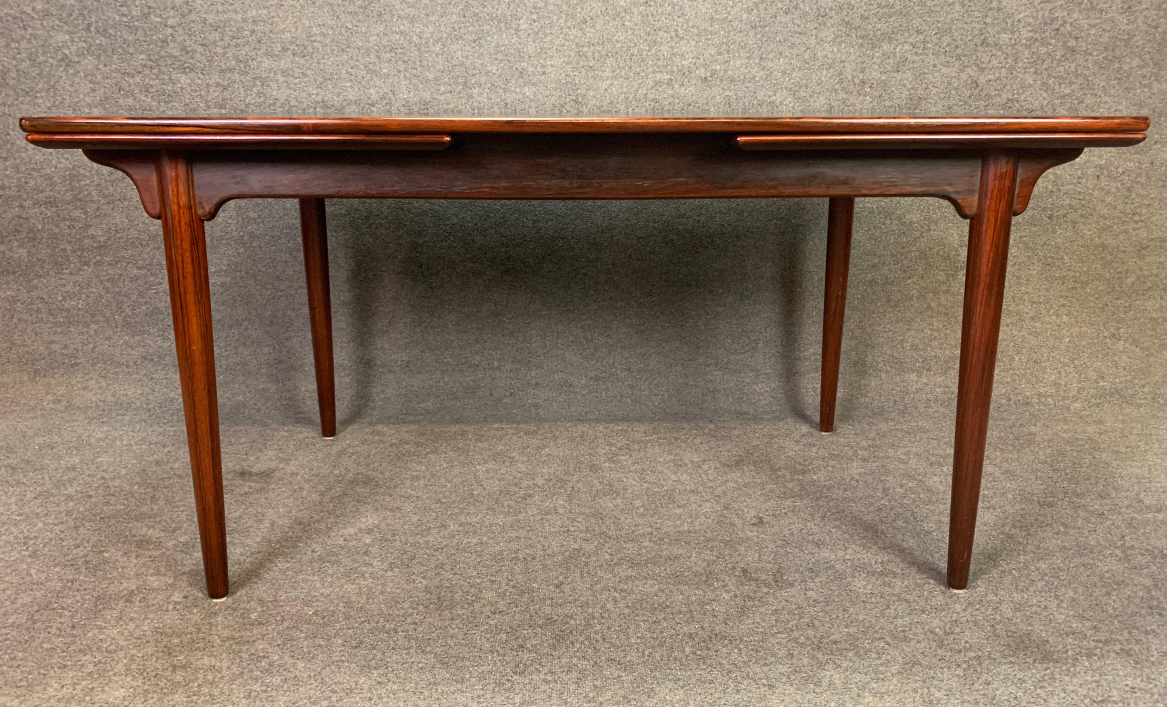 Here is a beautiful Scandinavian Modern dining table in rosewood designed by Gunni Omann and manufactured by Omann Jun in Denmark in the 1960s.
This exquisite table features a vibrant wood grain, a sculptural frame, two draw leaves and four solid