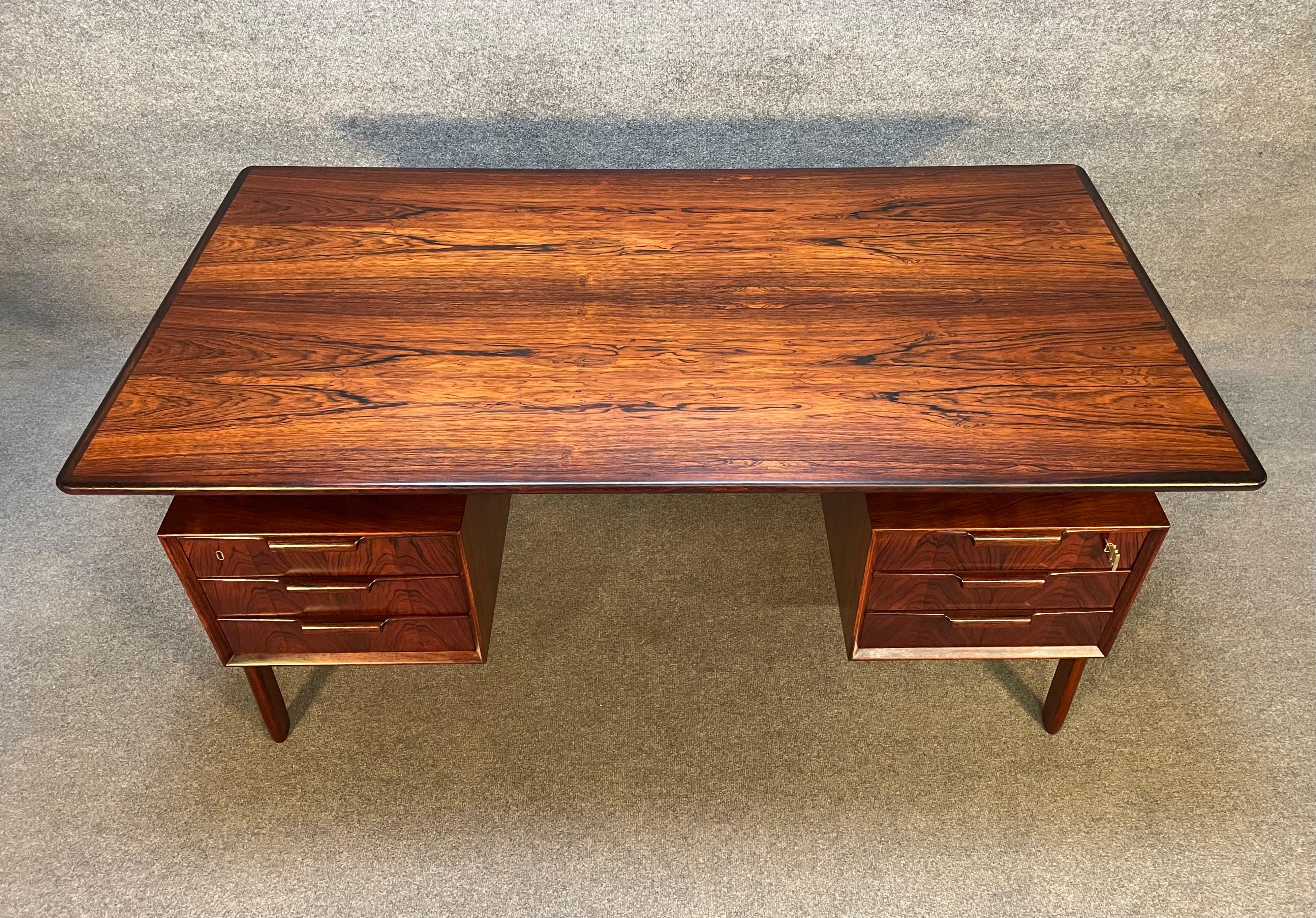 Here is the iconic Model 75 desk designed by Gunni Omann and manufactured by Omann Jun Mobelfabrik which was recently imported from Denmark to California before its restoration. This stunning 1960's Scandinavian modern desk in Brazilian rosewood